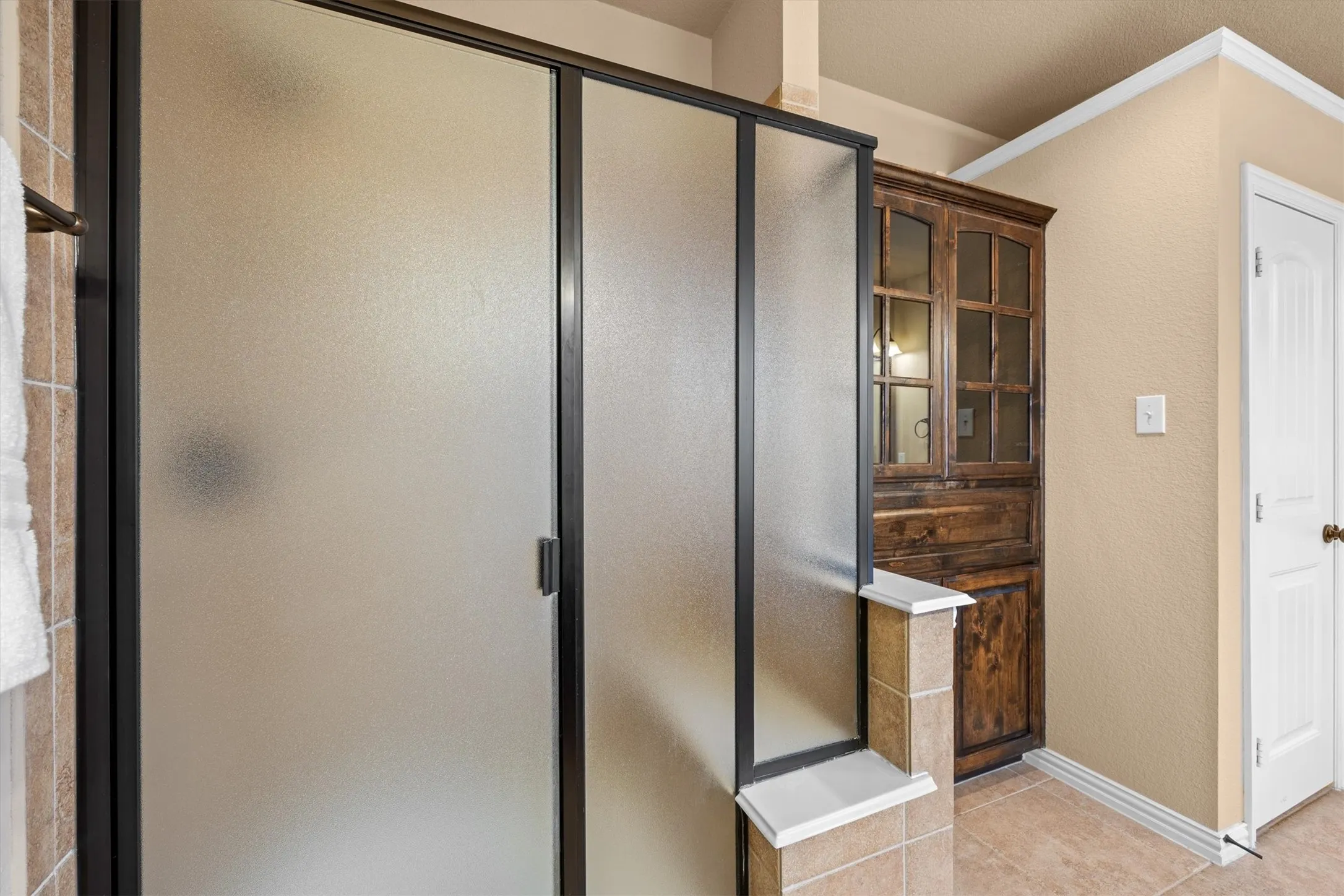 The primary bathroom also features a separate shower and built-in cabinetry for towels and essentials.