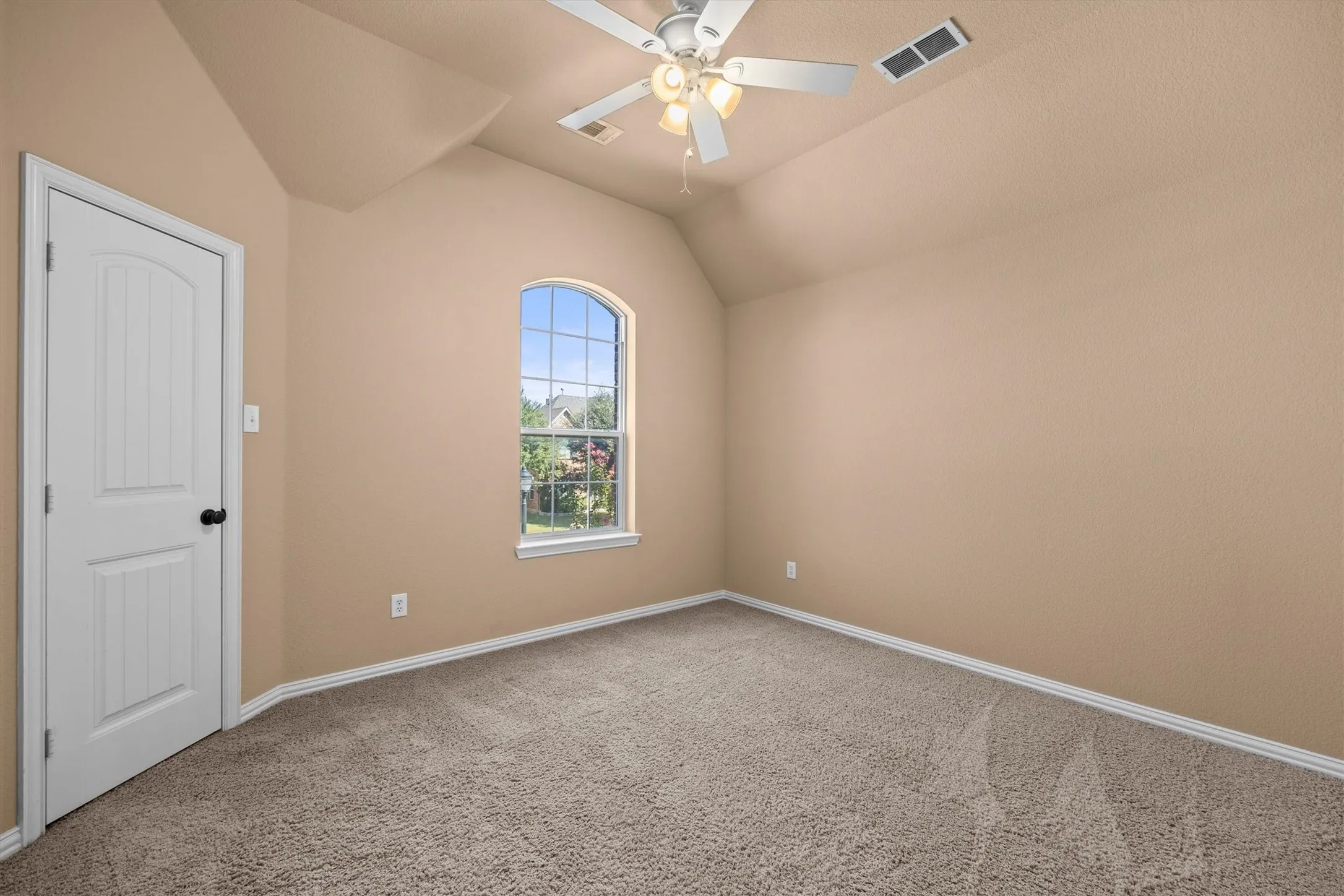 An arched window and vaulted ceiling add character to this secondary bedroom.