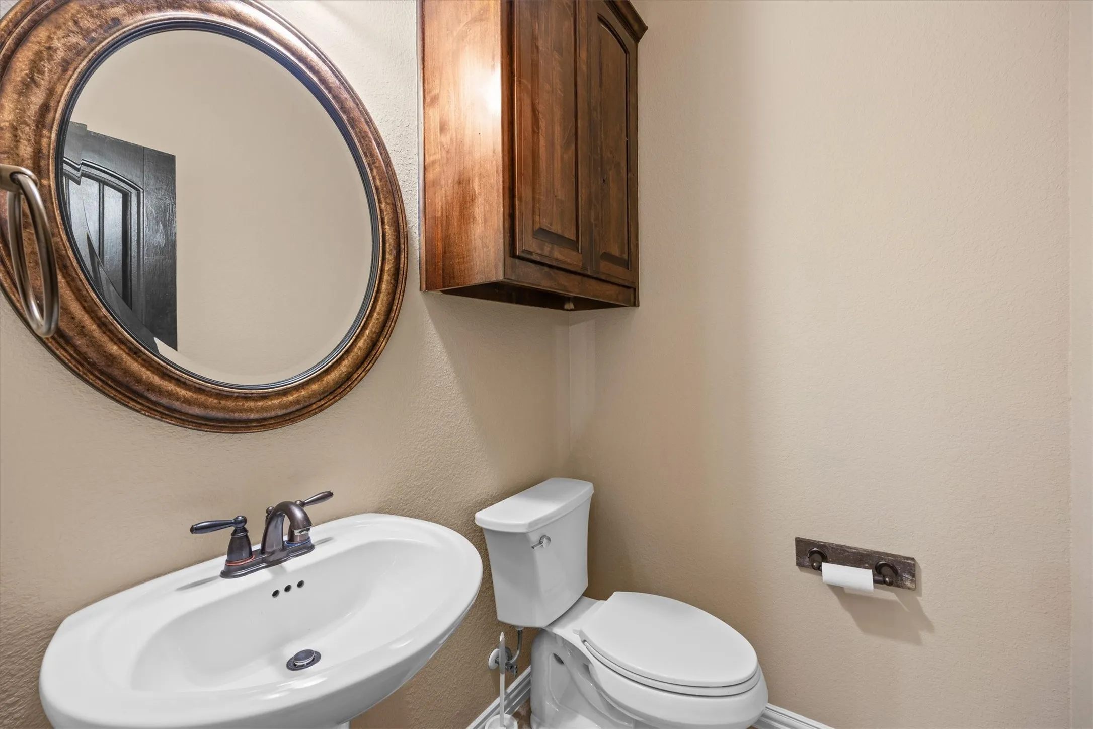 This charming powder bath features a pedestal sink and a cabinet for extra storage.