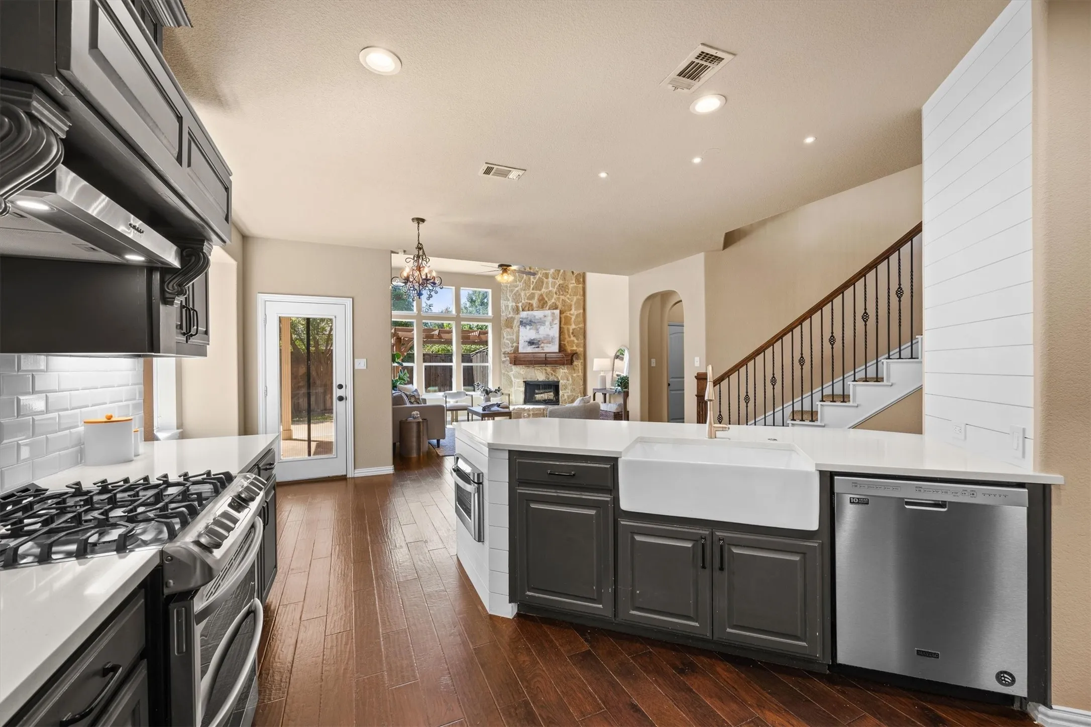 A farmhouse sink and gas range complement the kitchen’s open connection to the living spaces.