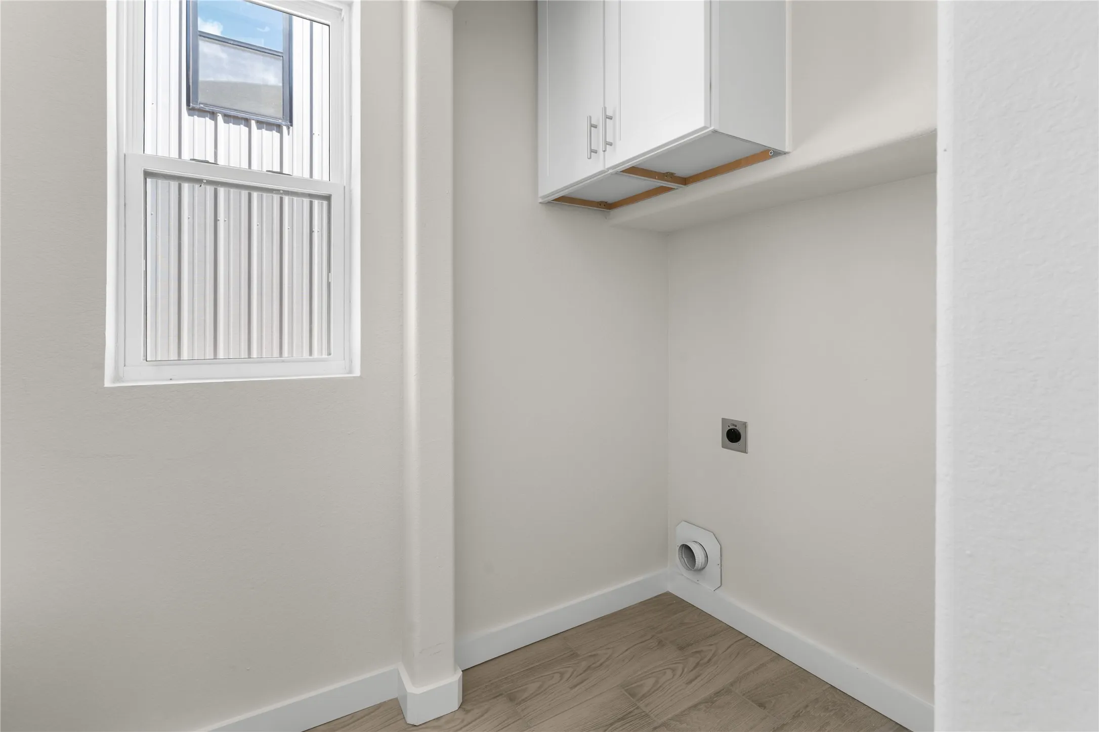 Utility space featuring wood-finish flooring, white walls, and built-in white cabinetry