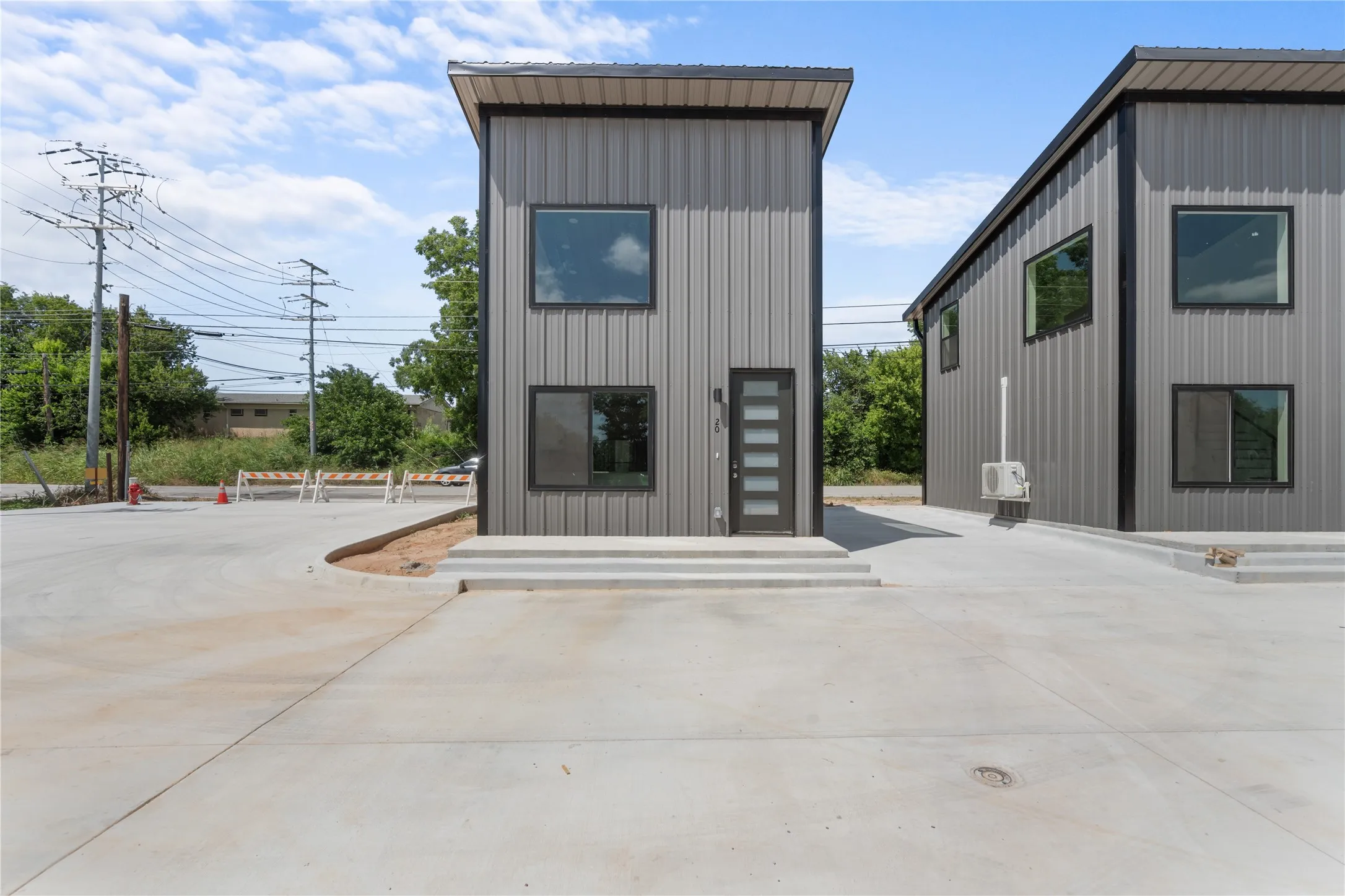 Modern exterior featuring vertical metal siding, black trim accents, a contemporary front door with privacy glass, and multiple large windows