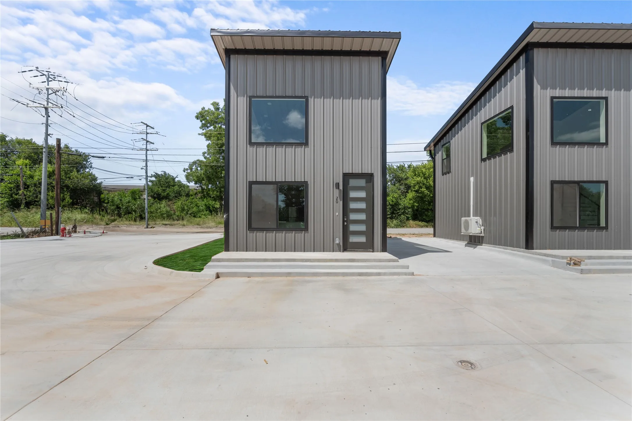 Contemporary exterior with vertical metal siding, multiple windows, and a modern entry door featuring frosted glass panels
