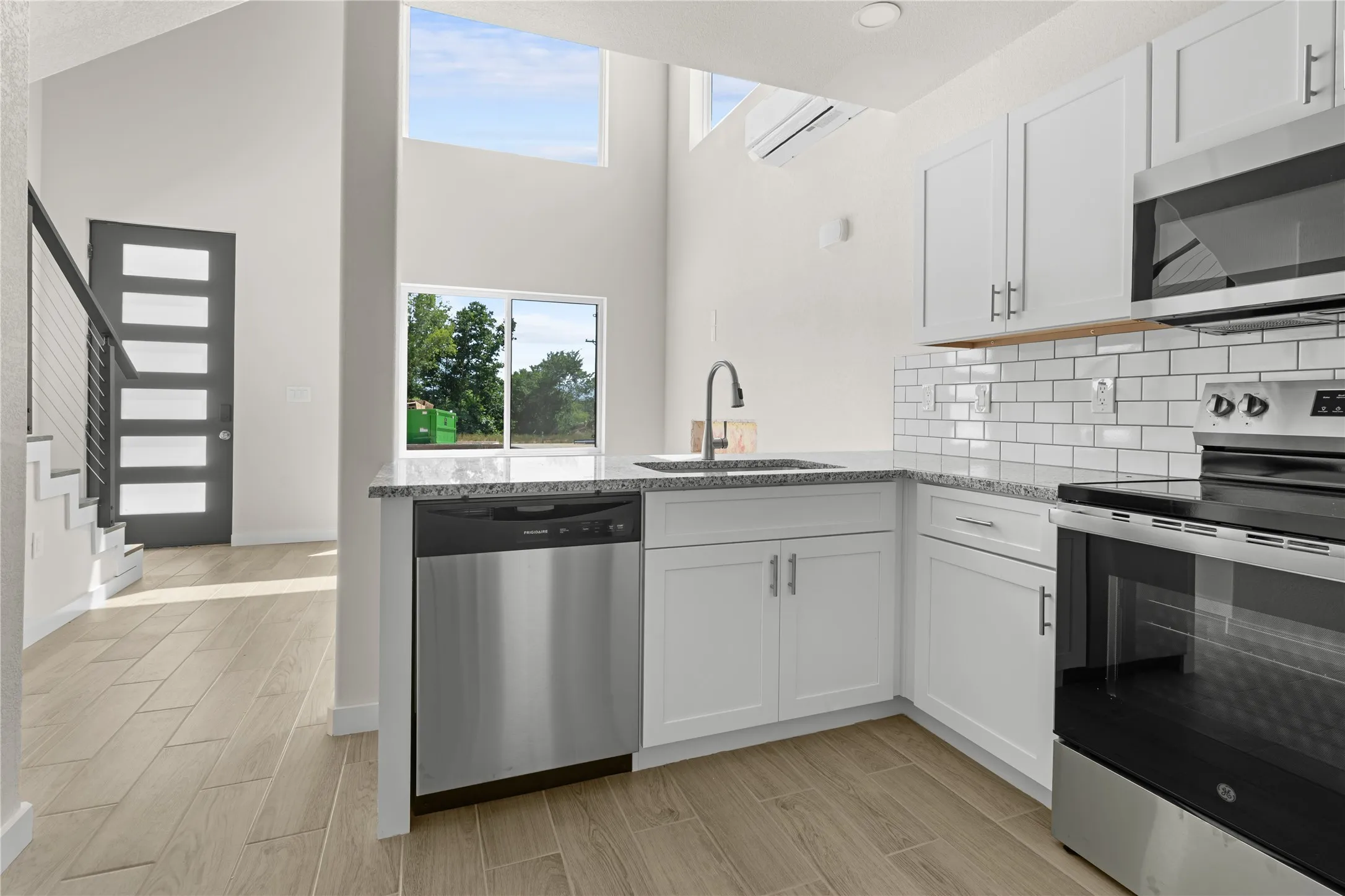 Kitchen featuring white shaker cabinetry, stainless steel appliances, granite countertops, and subway tile backsplash