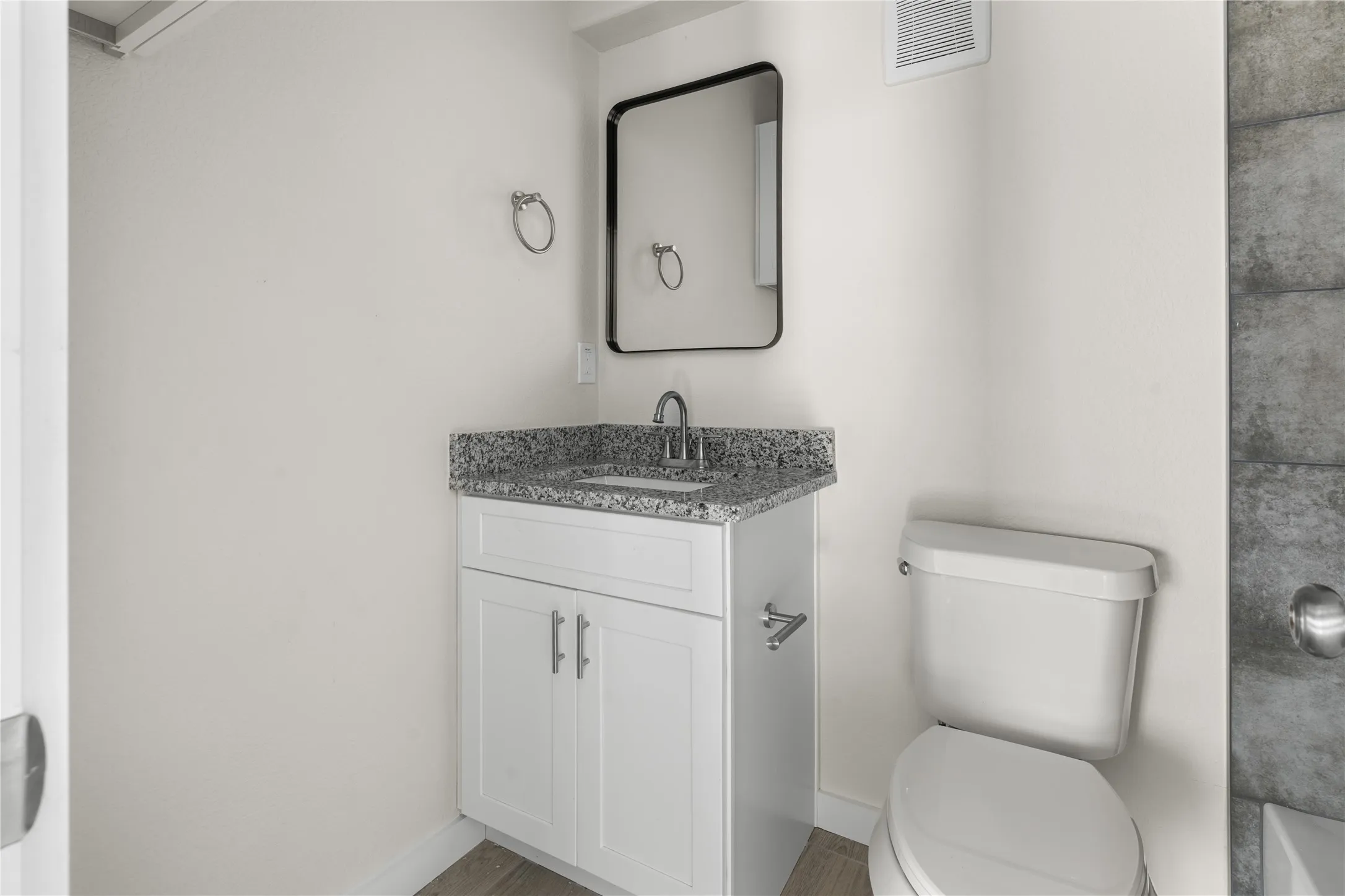 White vanity with a speckled countertop, undermount sink, and chrome faucet