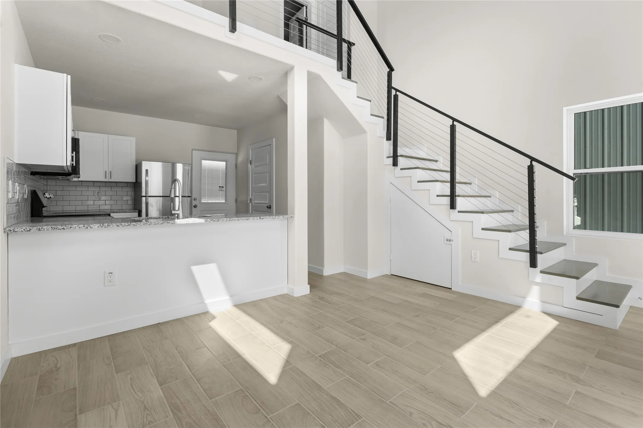 Open-concept kitchen with white cabinetry and stainless steel appliances