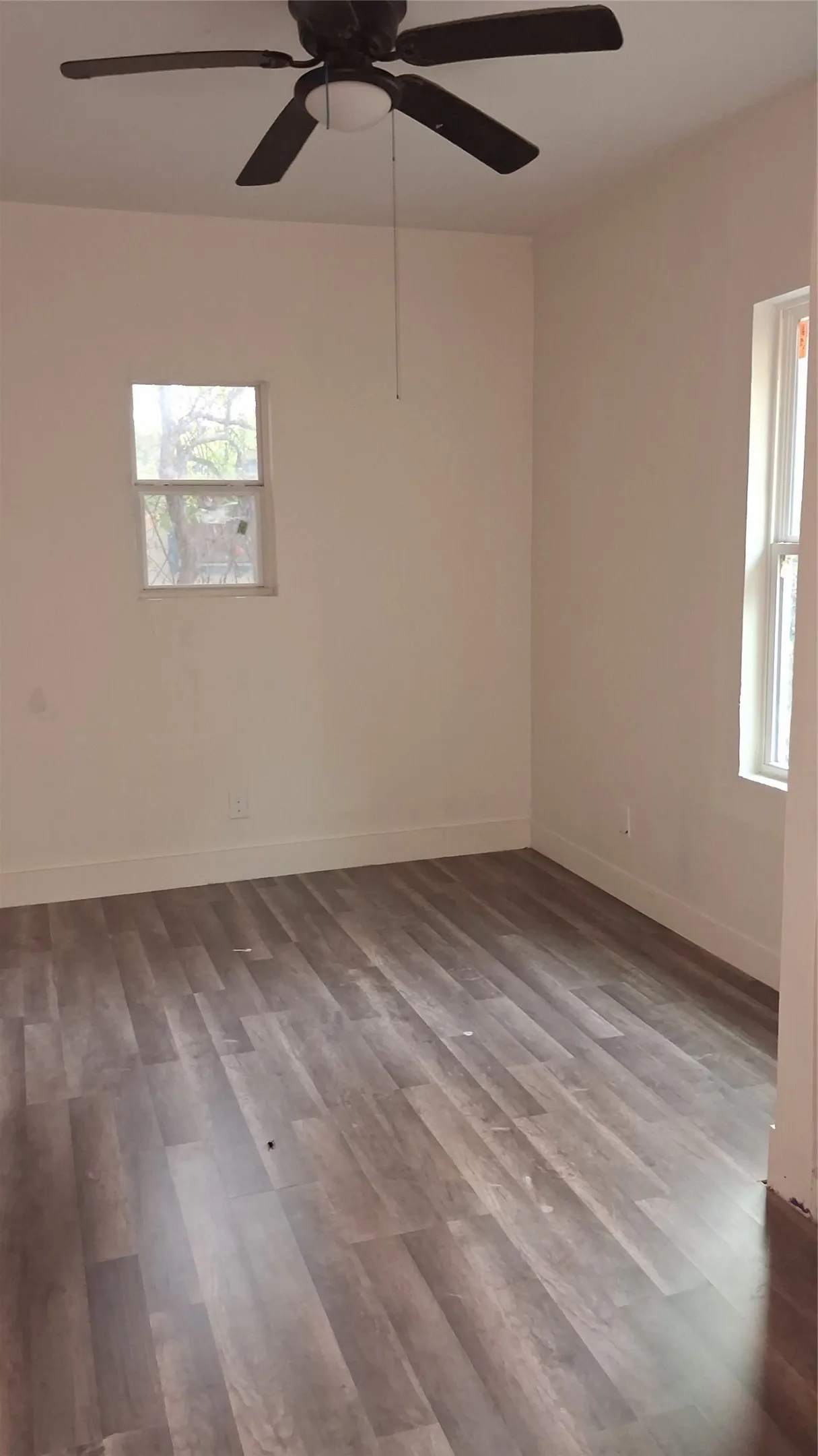 Wood-finish flooring with neutral wall tones and a ceiling fan with integrated lighting
