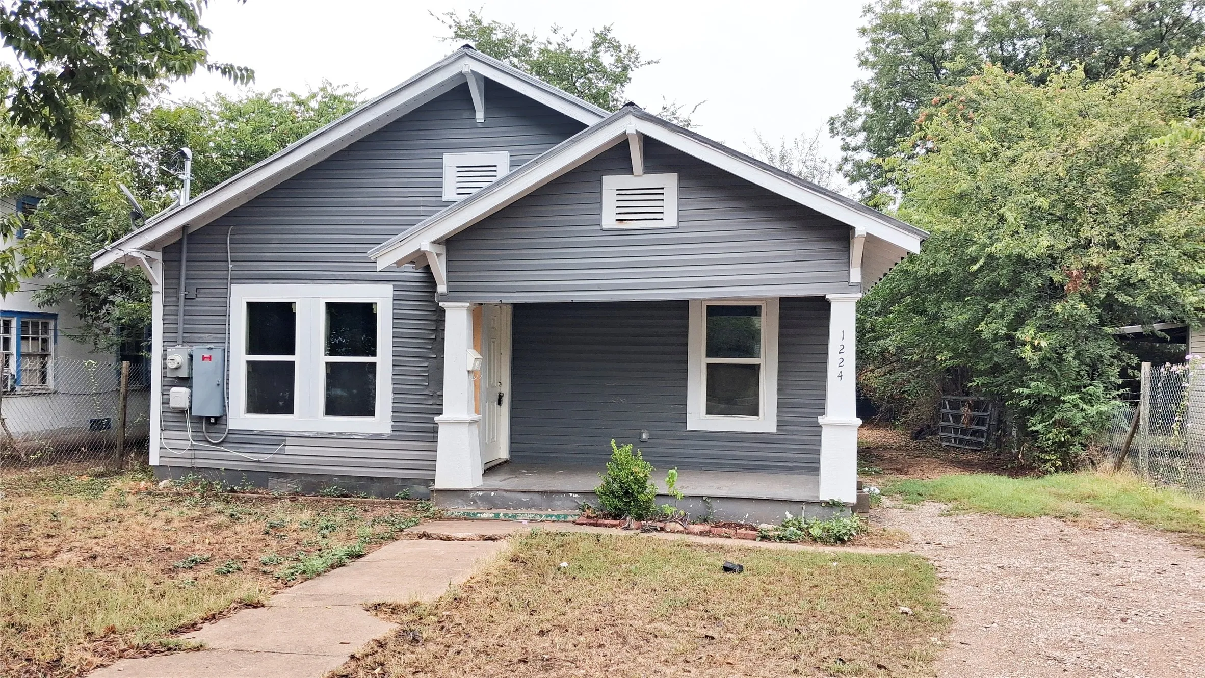Gabled roofline, gray horizontal siding, white trim, covered front porch, and front entry
