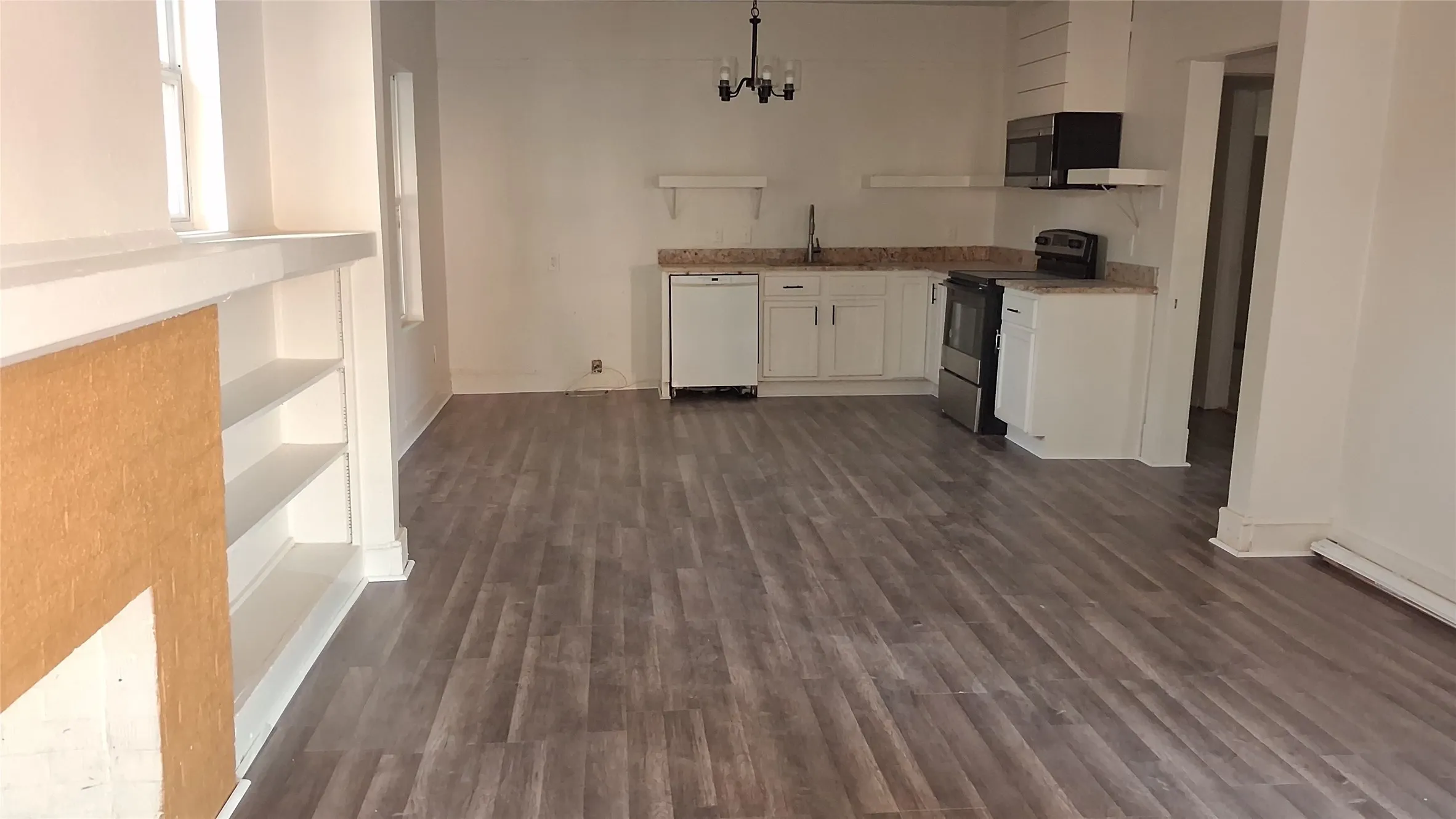 Wood-finish flooring, built-in shelving, white cabinetry, granite-finish countertops, and integrated kitchen appliances