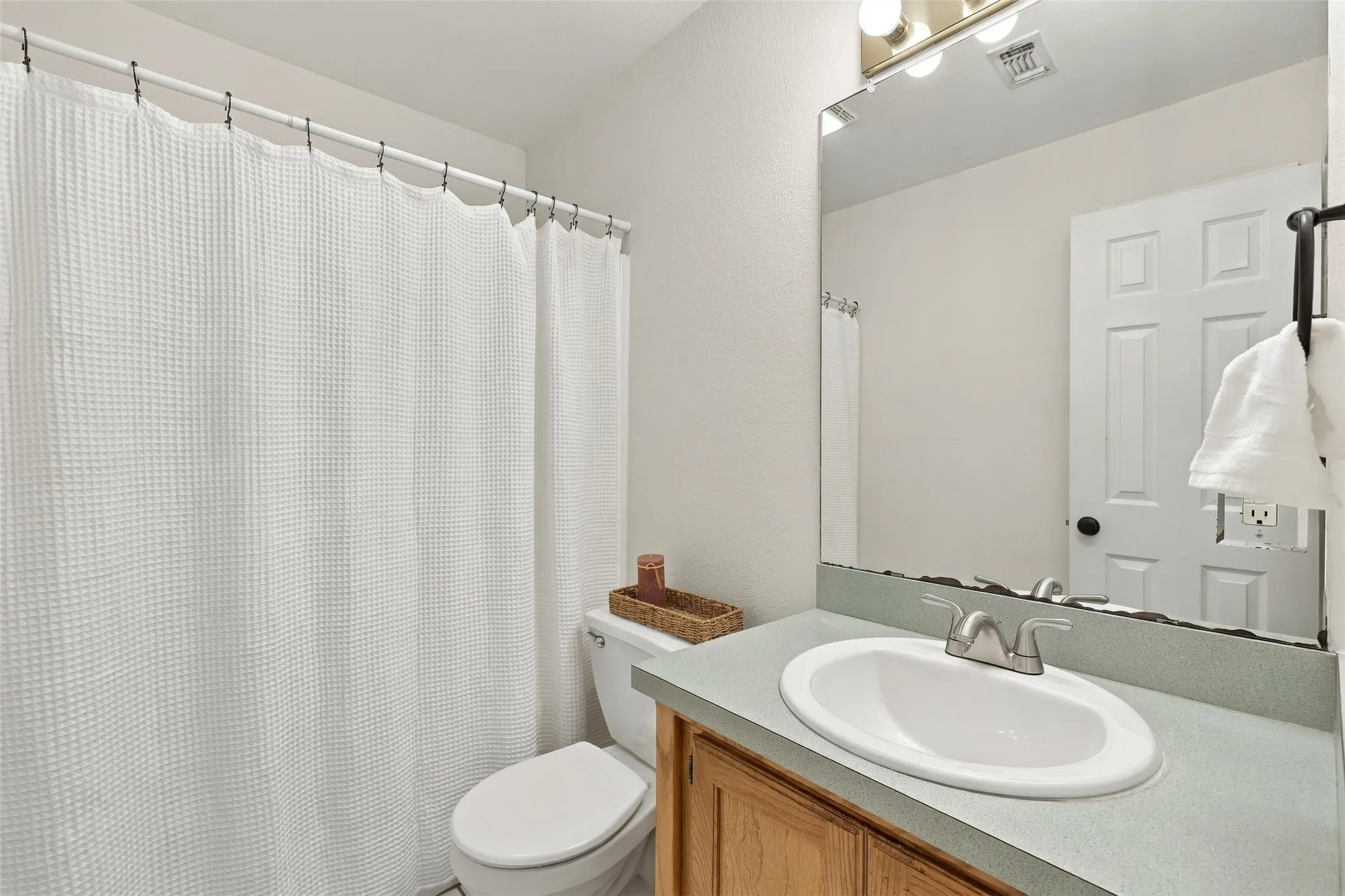 Bathroom: Convenient bathroom featuring a single-sink vanity, wood cabinetry, a large mirror, and a tub-shower combination.