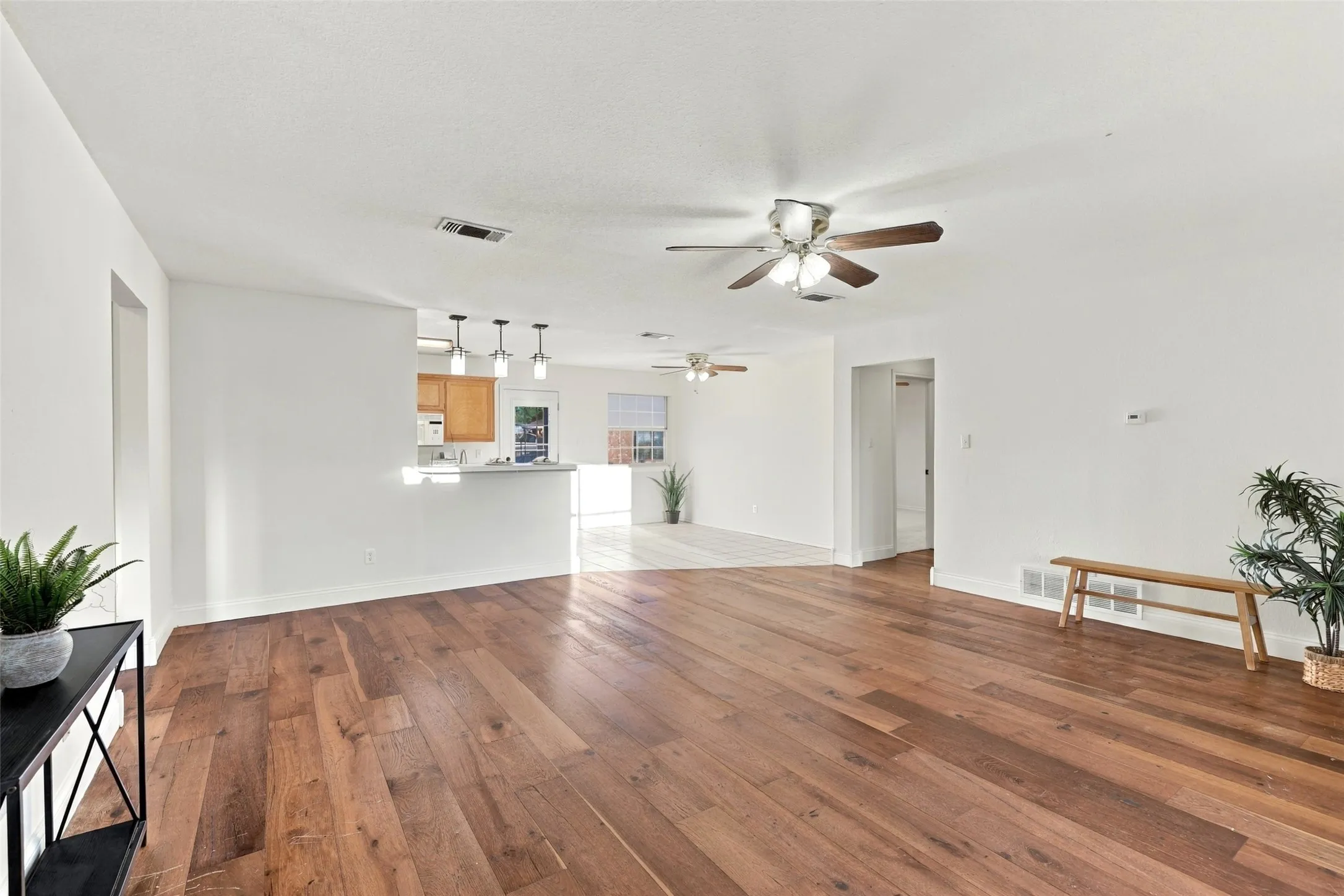Living Area: Spacious open-concept layout featuring rich wood flooring, neutral walls, and seamless flow into the kitchen and dining area.