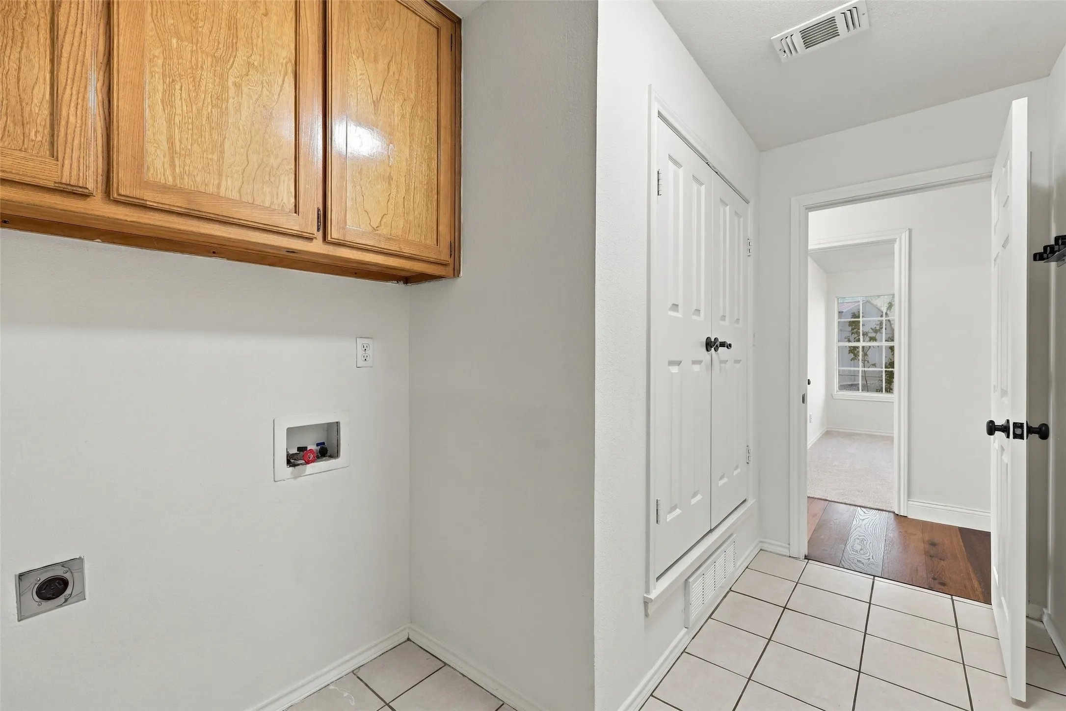 Laundry Area: Dedicated laundry space with washer and dryer hookups, overhead storage cabinets, and easy-care tile flooring.