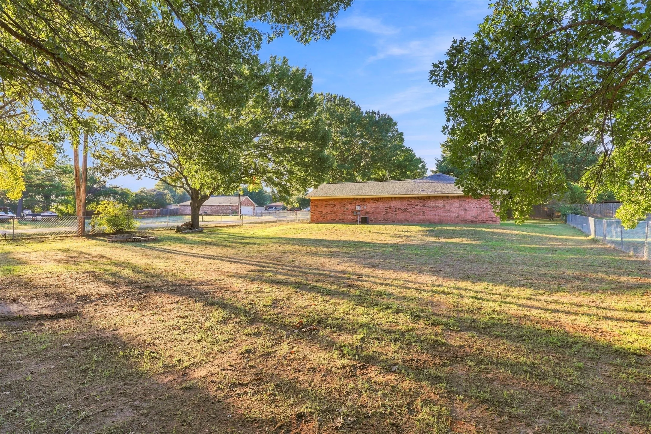 Rear Yard – Generous outdoor space with mature trees and views of the home's brick exterior.