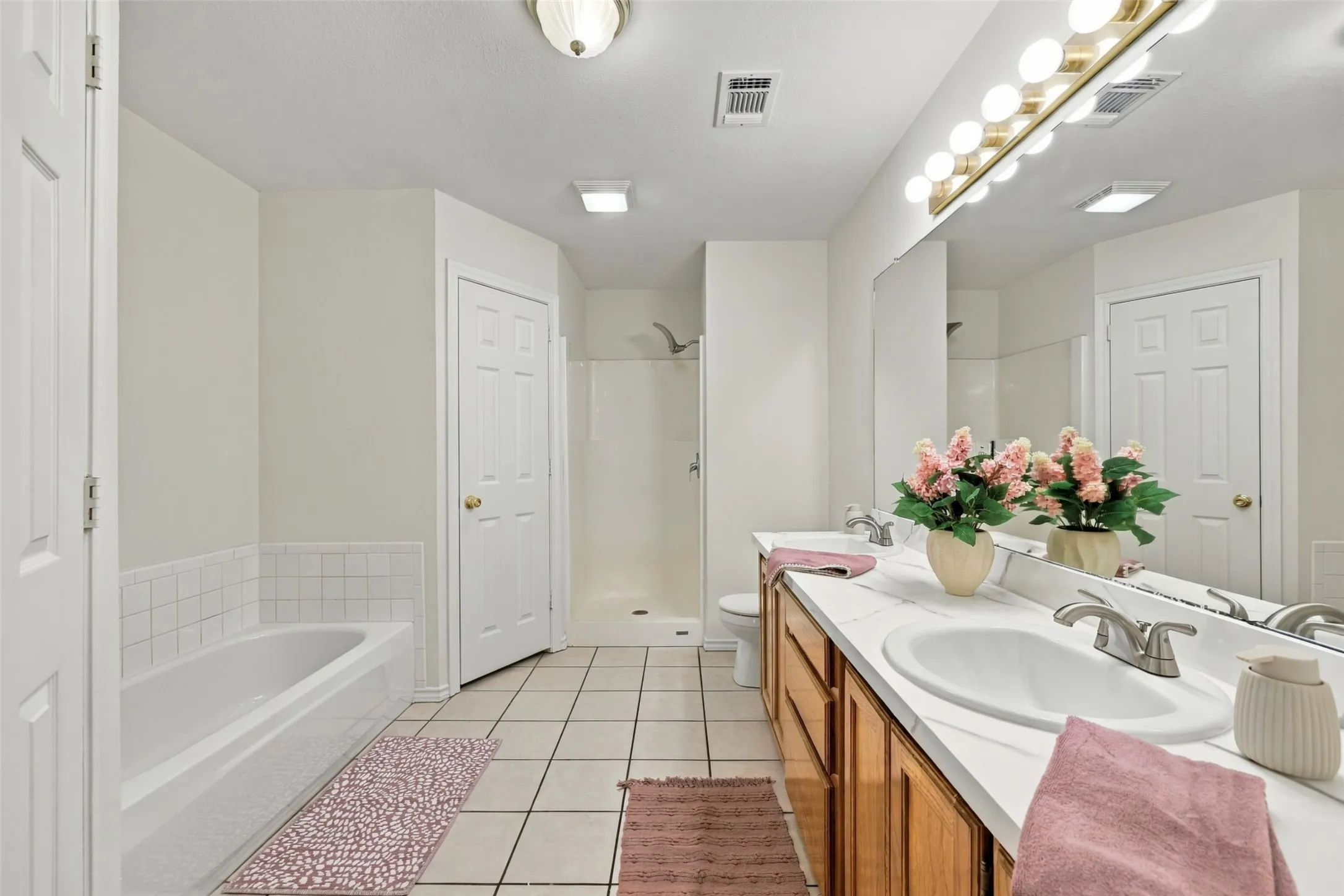 Bathroom: Generously sized bathroom featuring a double-sink vanity, soaking tub, separate shower, and tile flooring.
