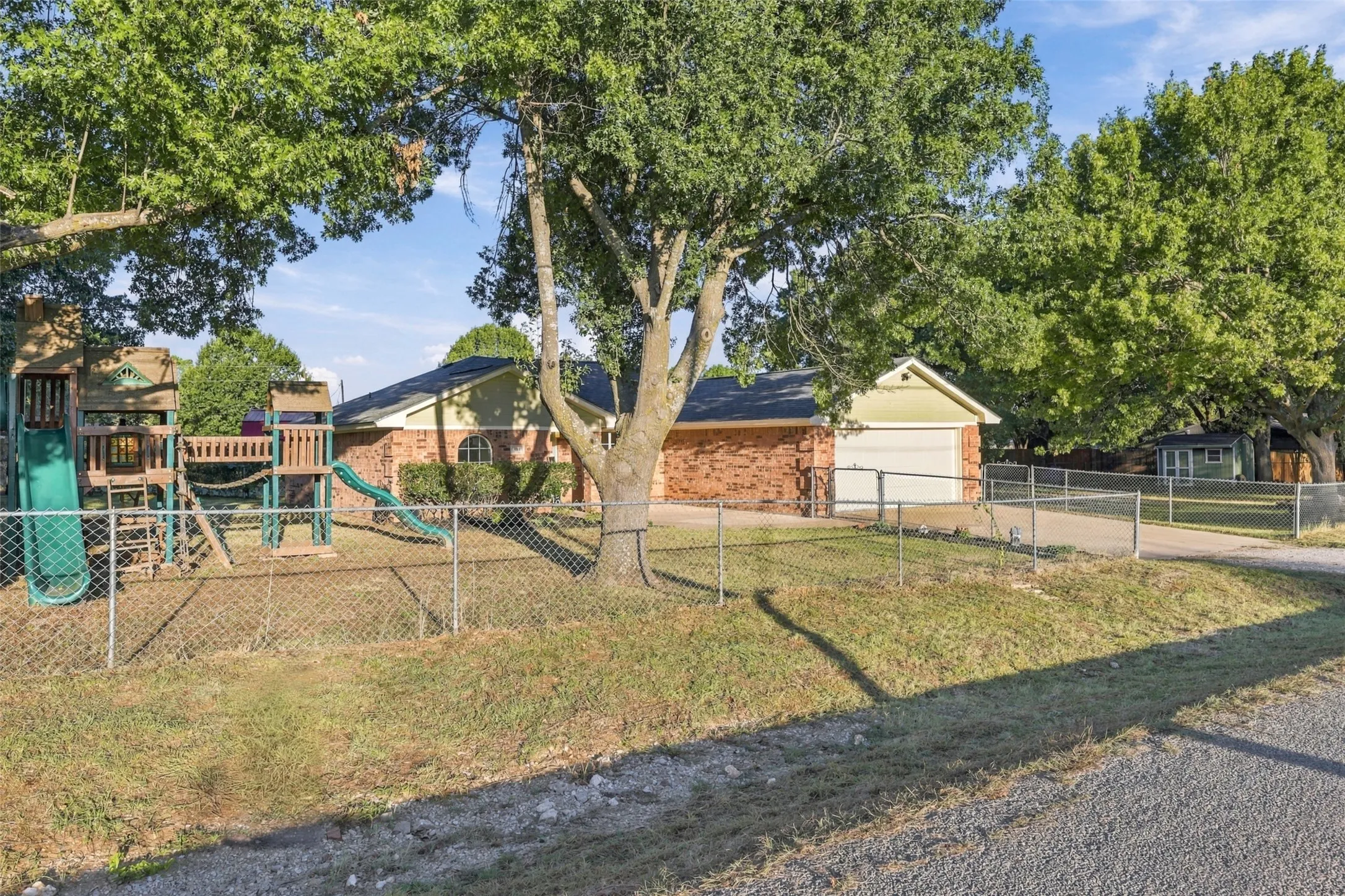 Front Yard – Fully fenced outdoor space with mature shade trees and playground.