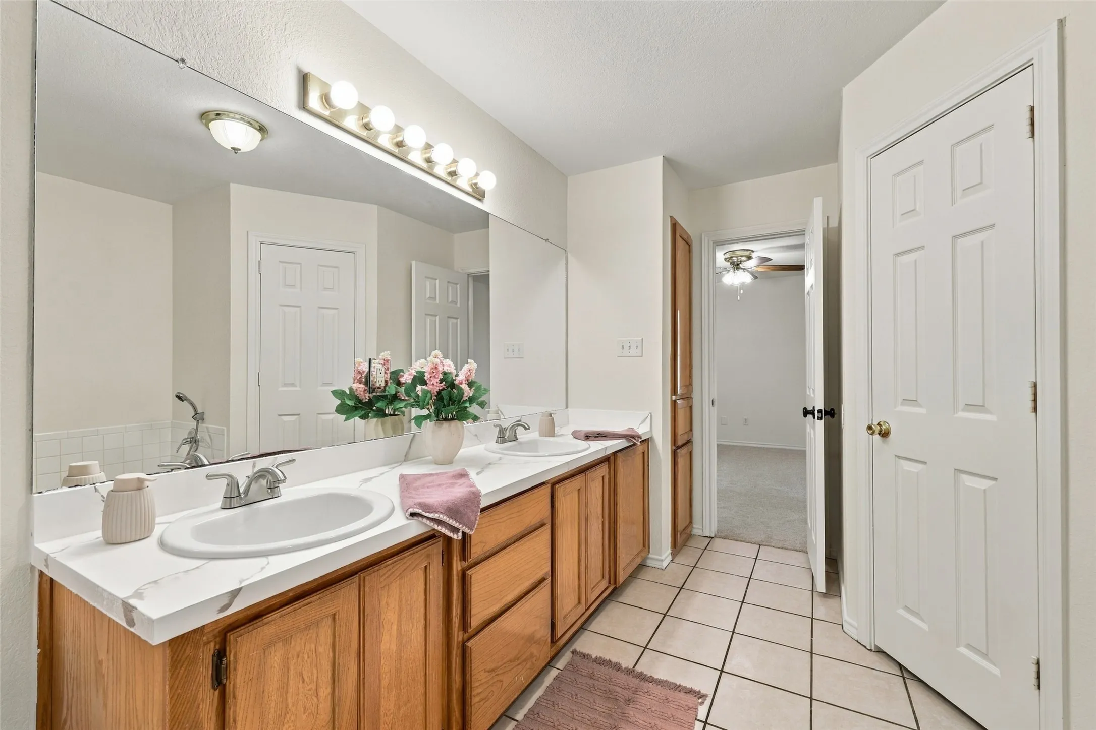 Bathroom: Extended double-sink vanity with wood cabinetry, a large wall mirror, and overhead vanity lighting.