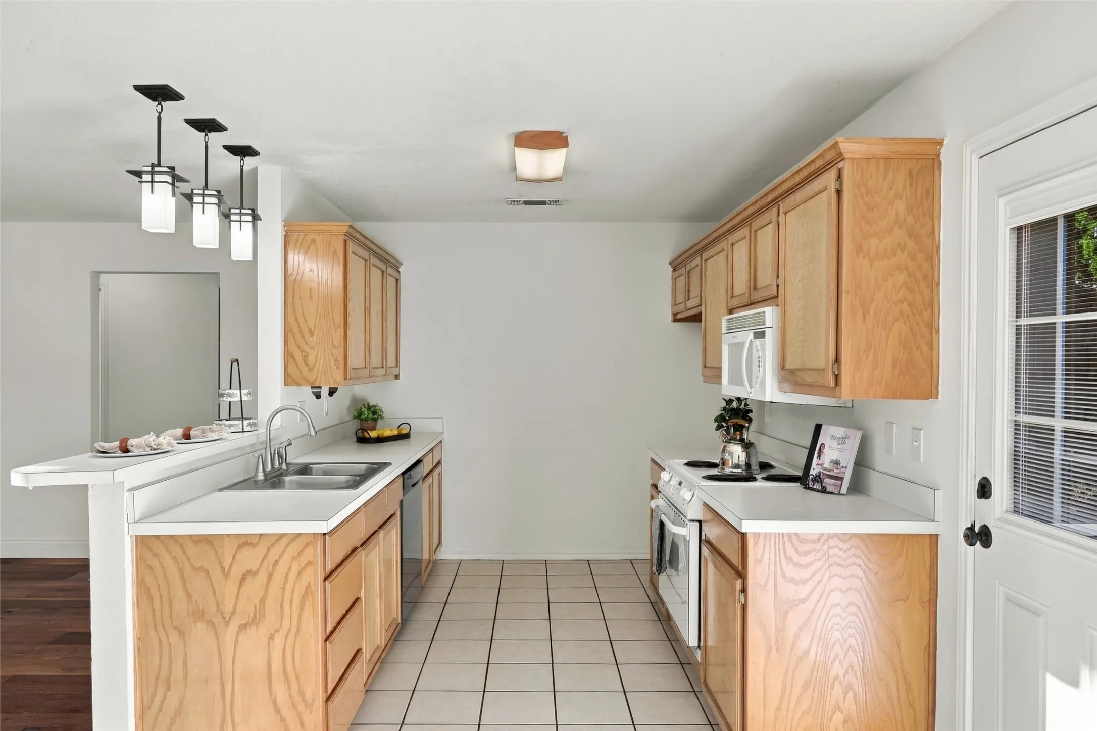 Kitchen: Functional galley-style layout offering generous cabinetry, ample counter space, tile flooring, and convenient access to the exterior.
