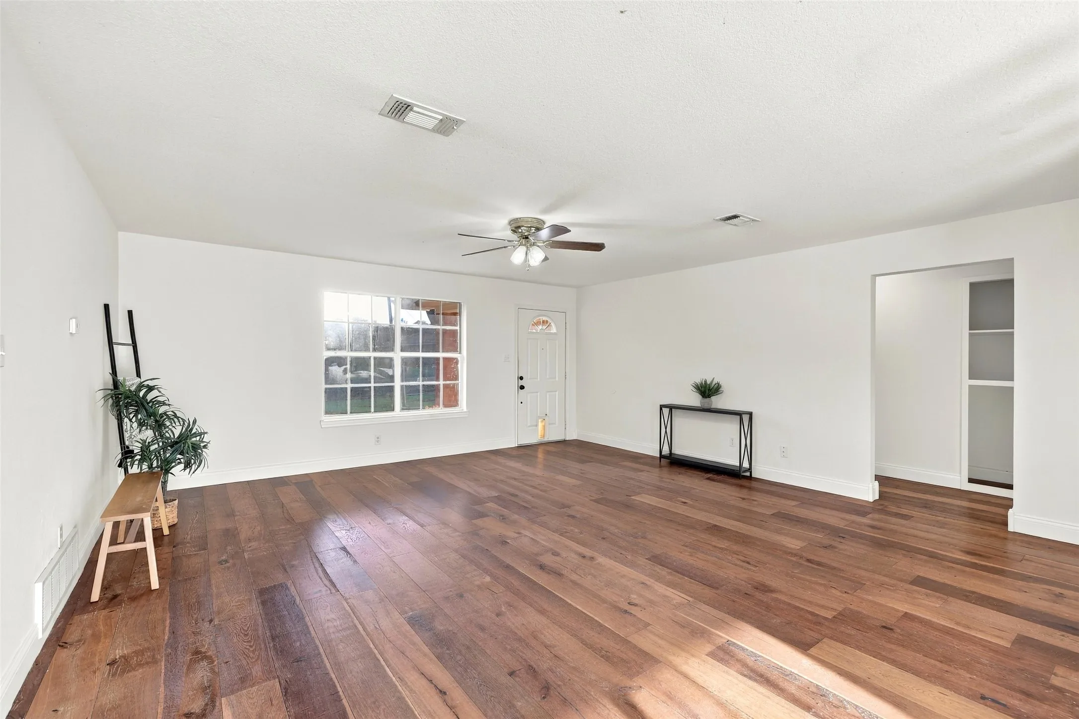 Living Area: Bright and inviting living room featuring a large front window, wood flooring, and flexible furniture arrangement options.