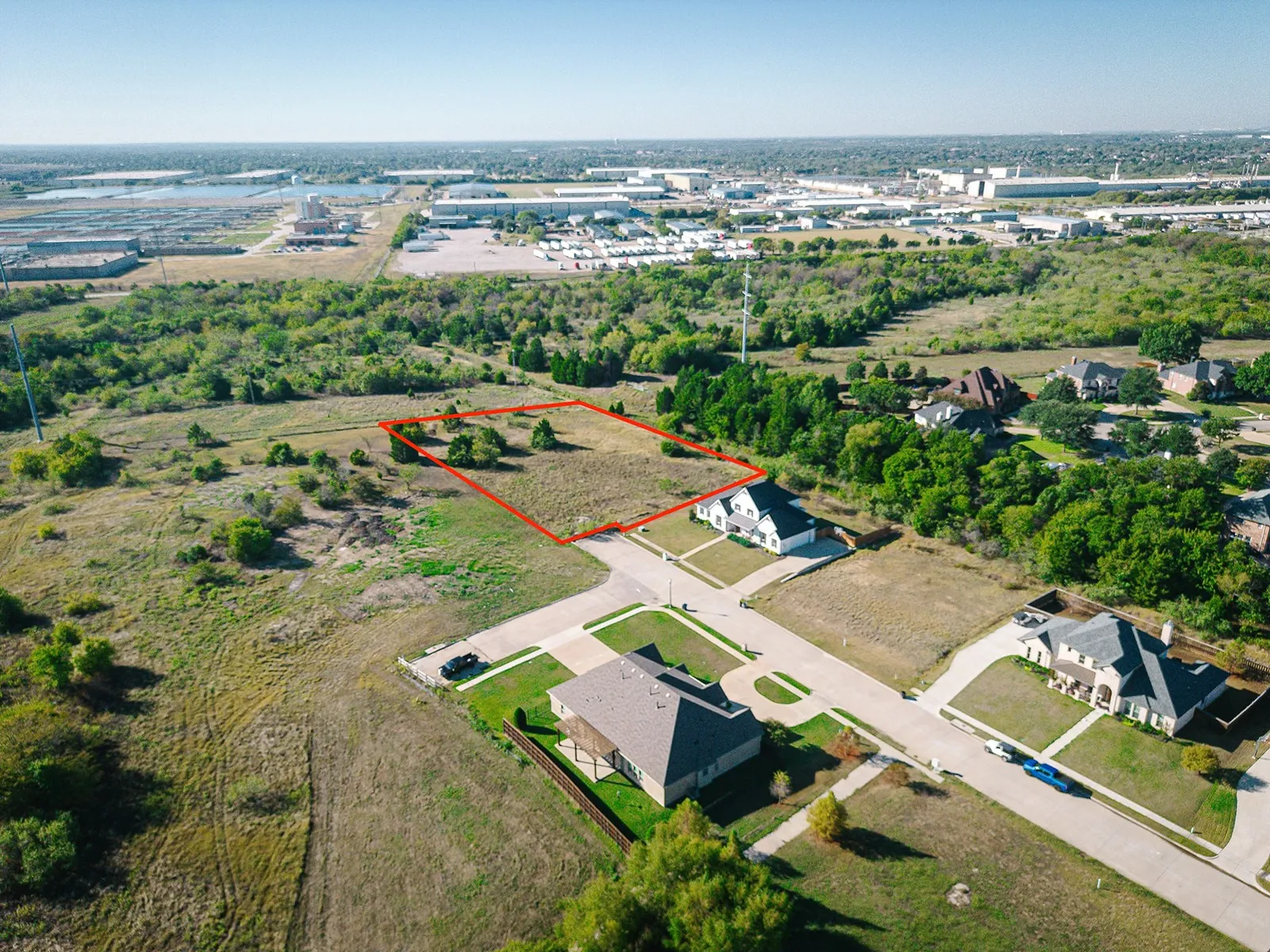 Expansive lot featuring a cleared building site, existing trees, and paved street access