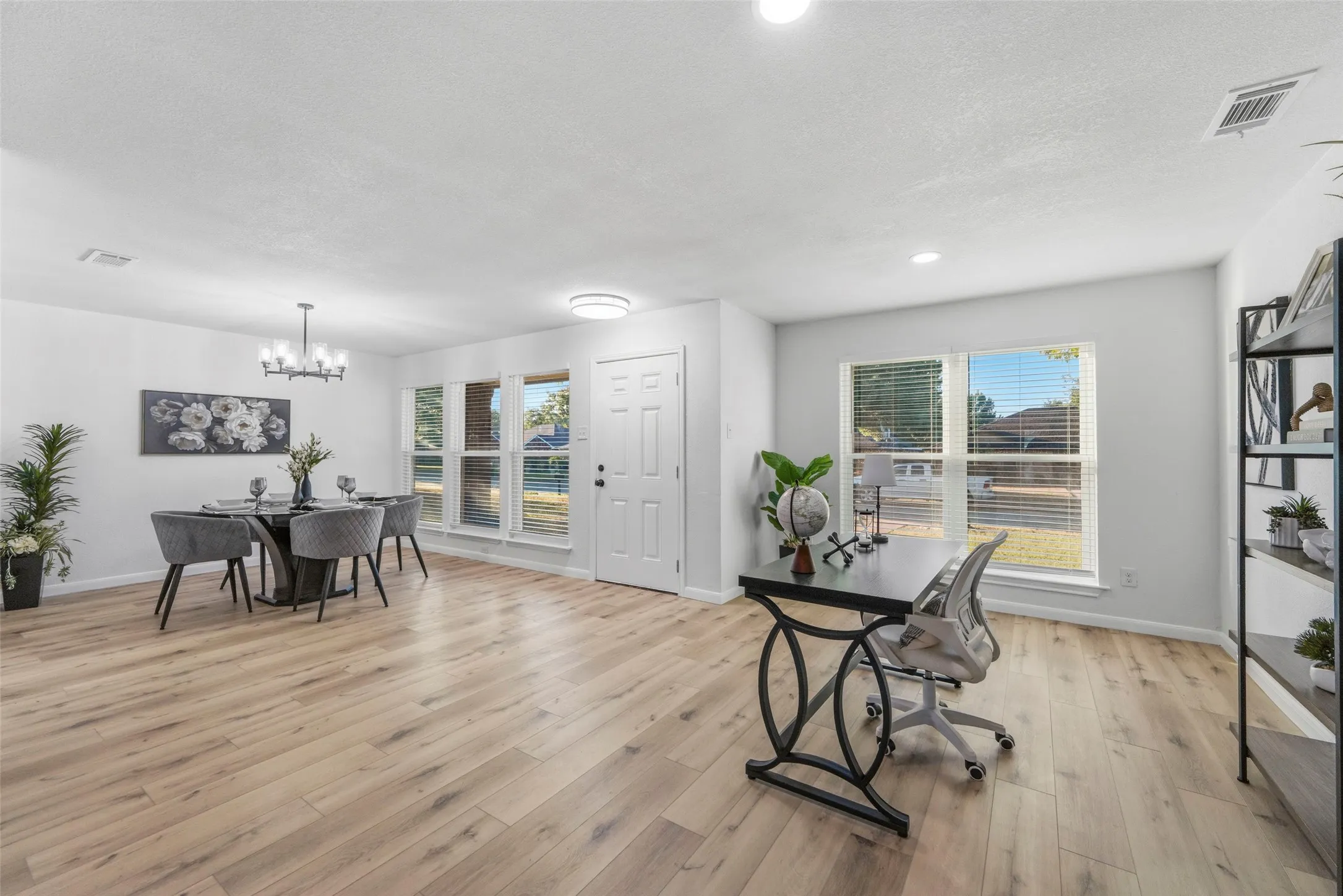 Spacious open-concept interior featuring light wood-finish flooring, multiple large windows, and recessed lighting