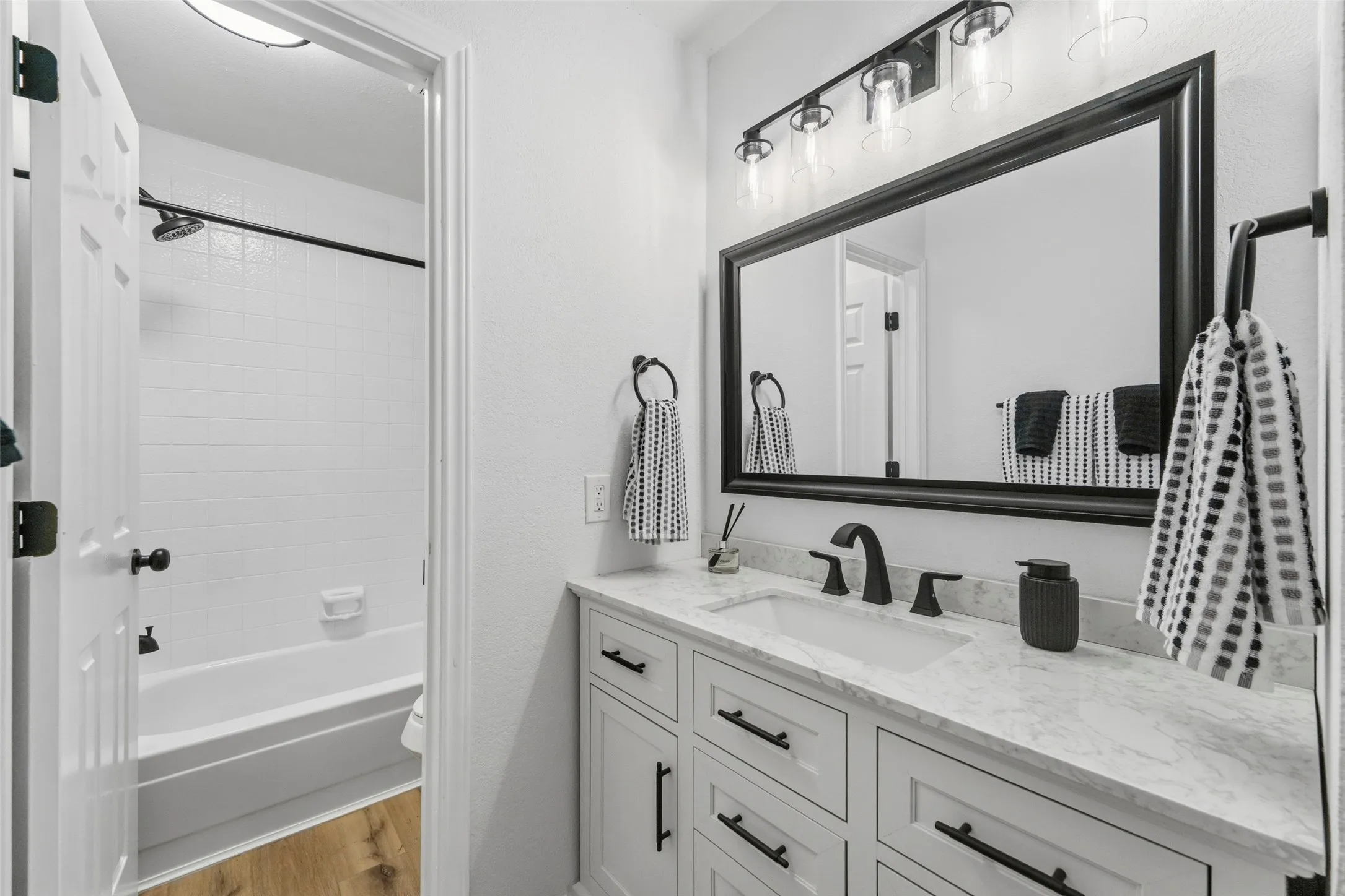 White vanity with integrated sink, black hardware, and a stone-finish countertop