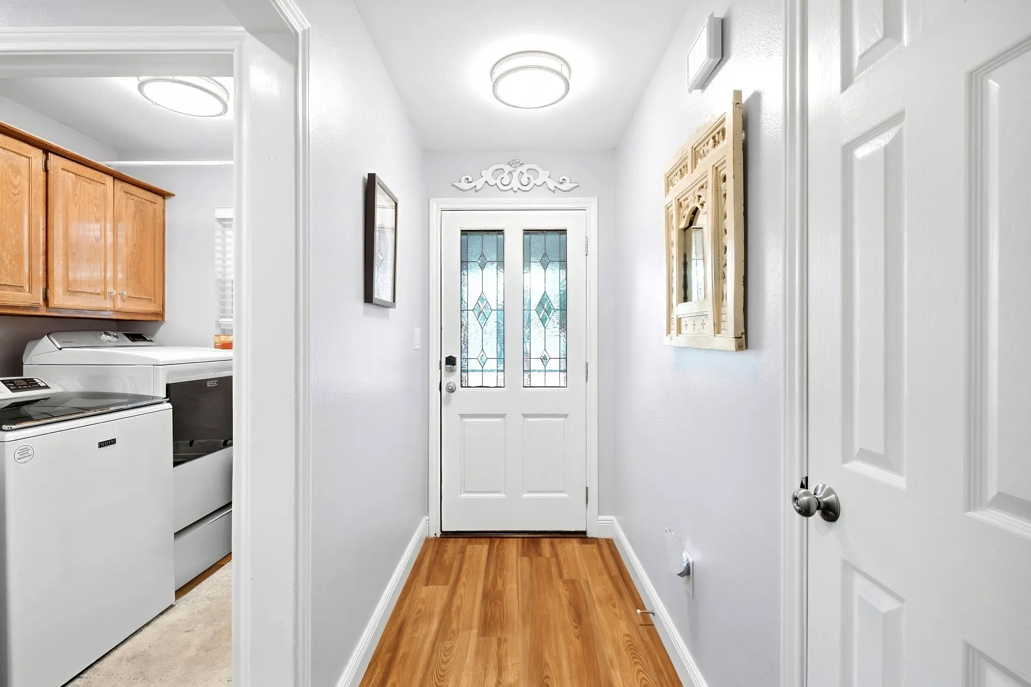 Wood-finish flooring throughout, white paneled interior doors, and a front entry door with decorative glass inserts
