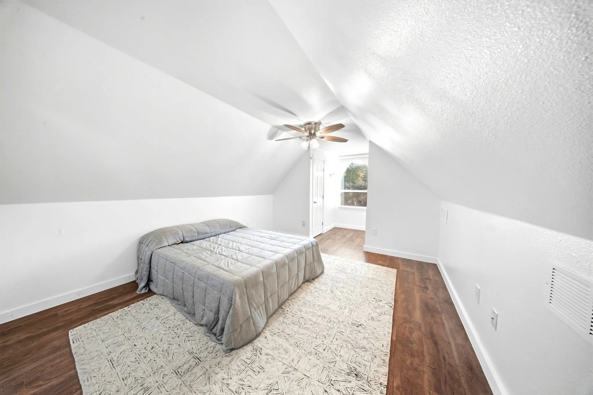 Virtually Staged Bedroom or Bonus Room
Slanted ceilings create architectural interest in this room featuring wood-finish flooring, a ceiling fan, and a window