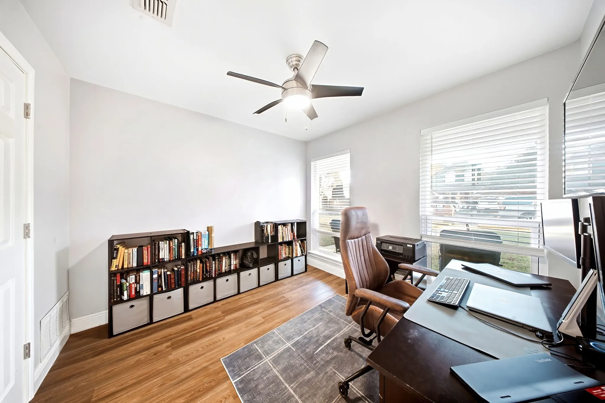 Wood-finish flooring, white walls, and a ceiling fan with integrated lighting