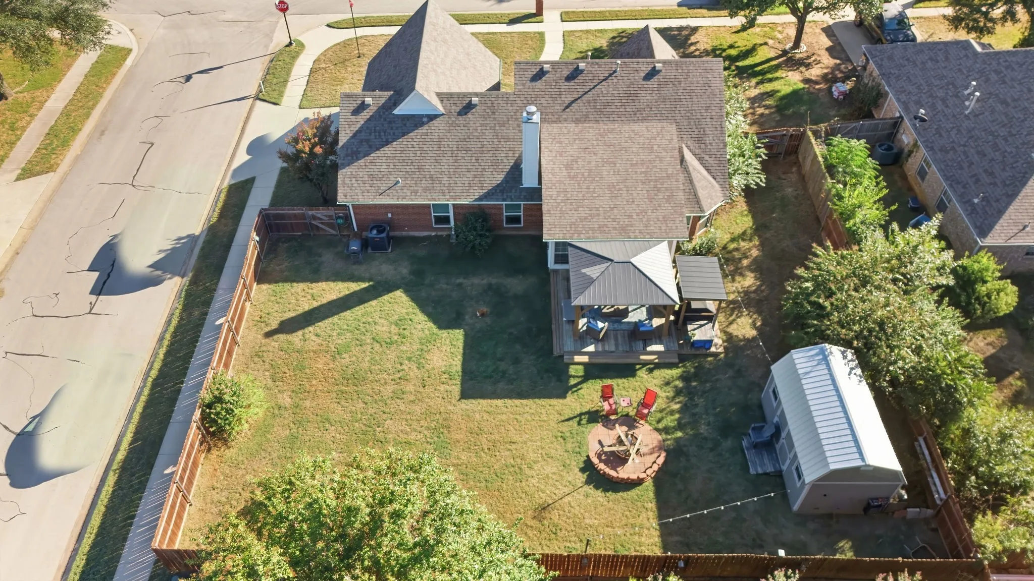 Expansive backyard with a privacy fence, wood deck, freestanding gazebo, and a storage shed