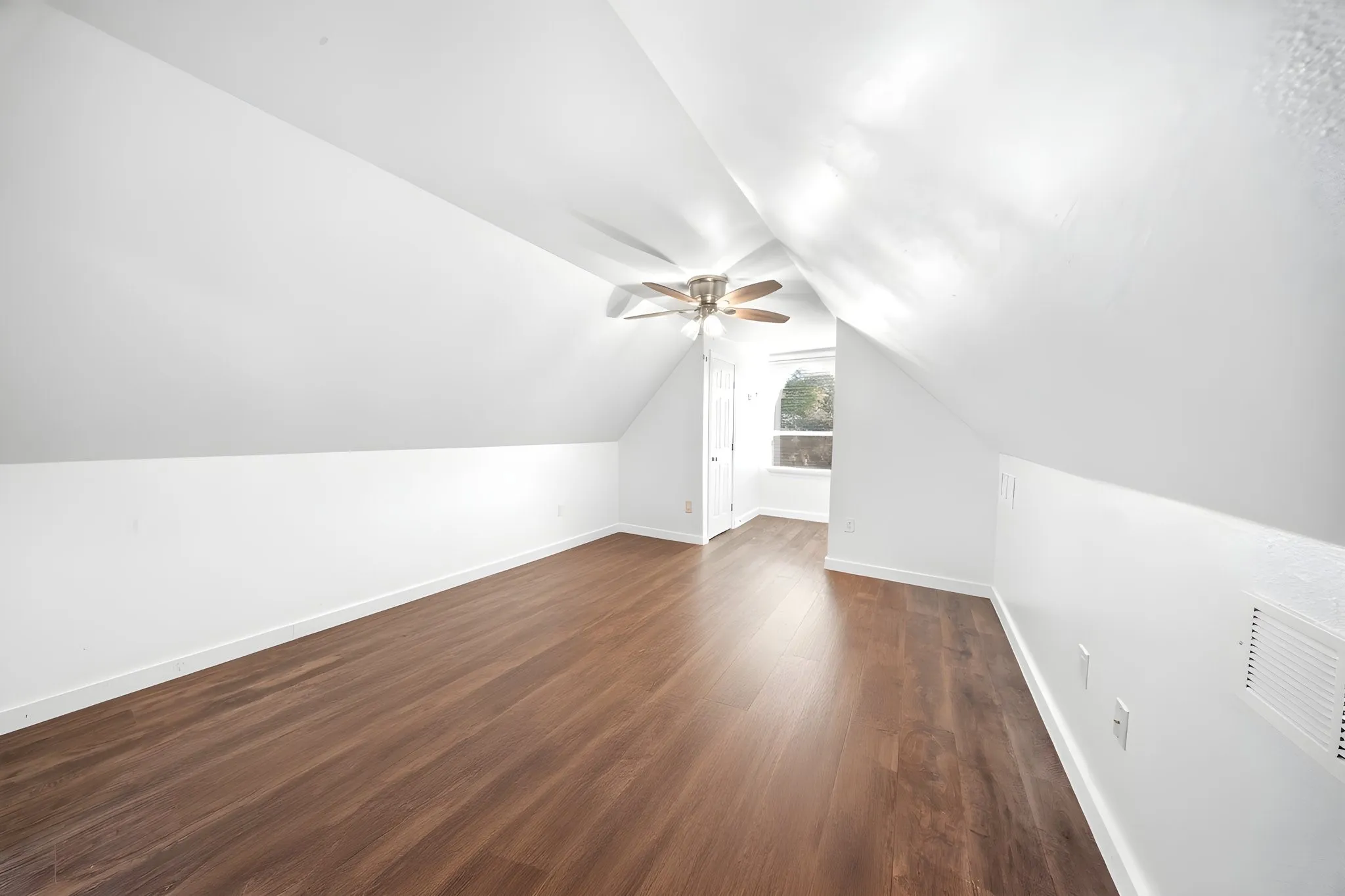 Bedroom or Bonus Room
Sloped ceiling room featuring wood-finish flooring, a ceiling fan, and a window