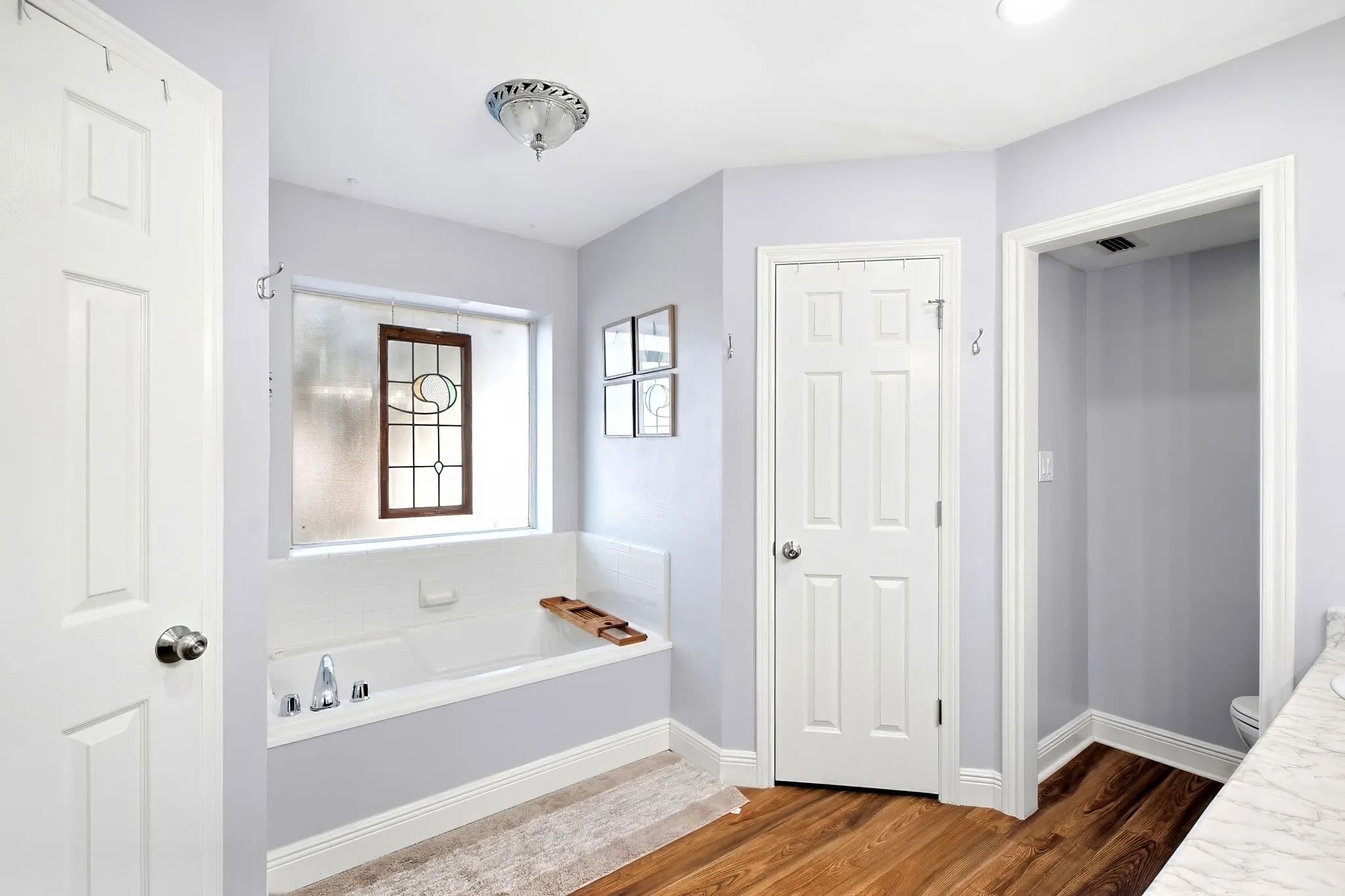 Built-in bathtub with polished chrome fixtures, accented by a decorative stained-glass window