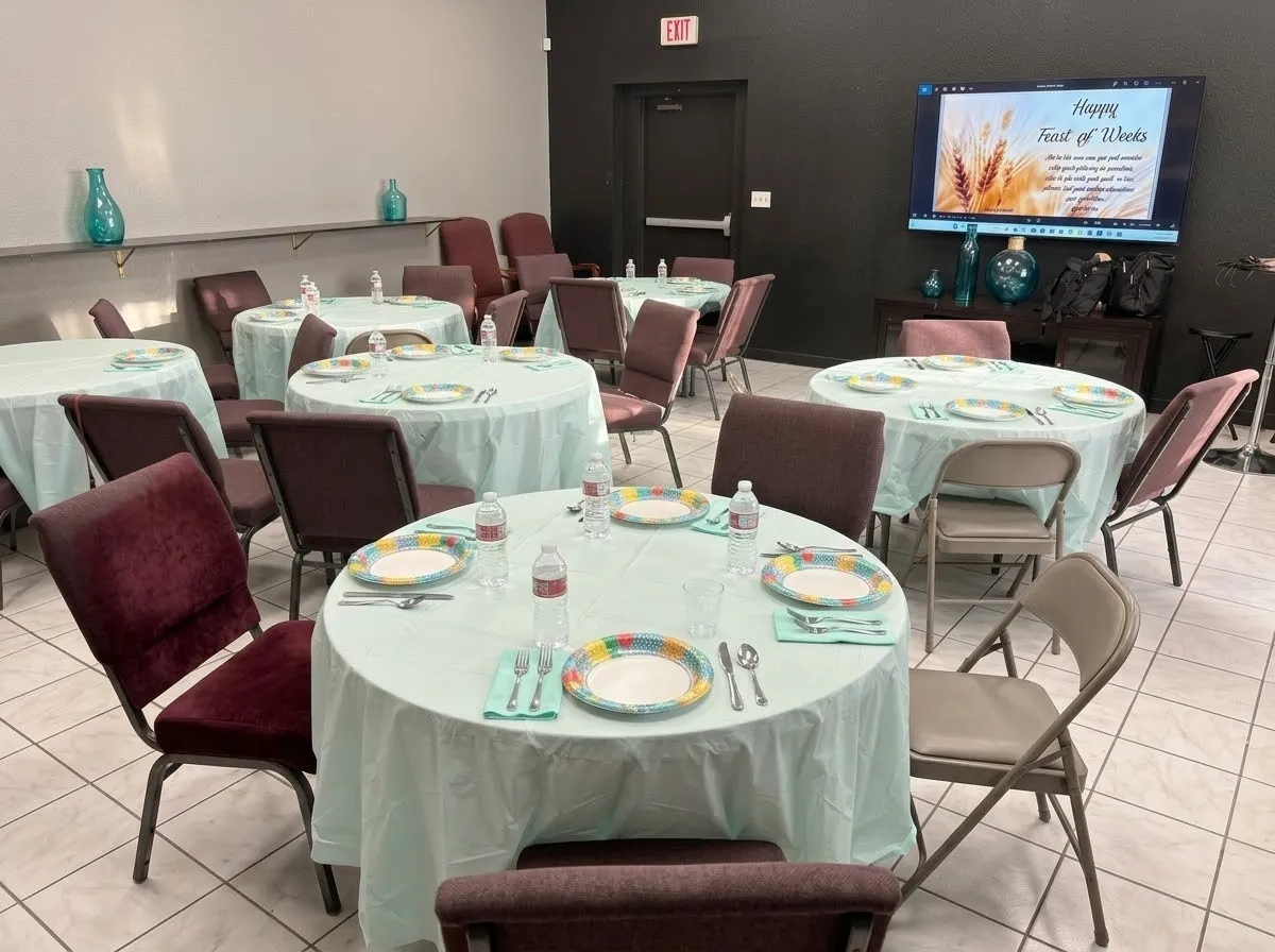 Spacious room featuring tile flooring, dark accent wall, and a mounted display screen. Used as fellowship hall right outside Kitchen