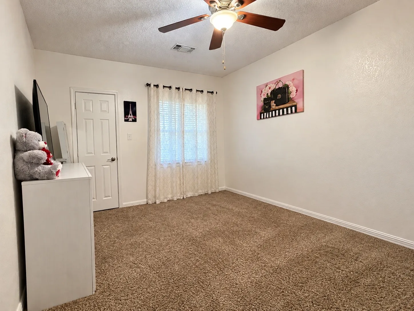 Carpeted room featuring a ceiling fan with integrated lighting, a panel door, and a window with blinds