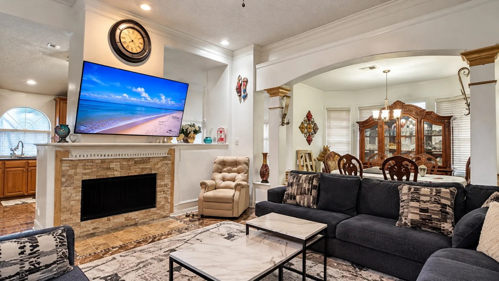 Stone-clad fireplace with mantel, arched entryways, crown molding, and recessed lighting