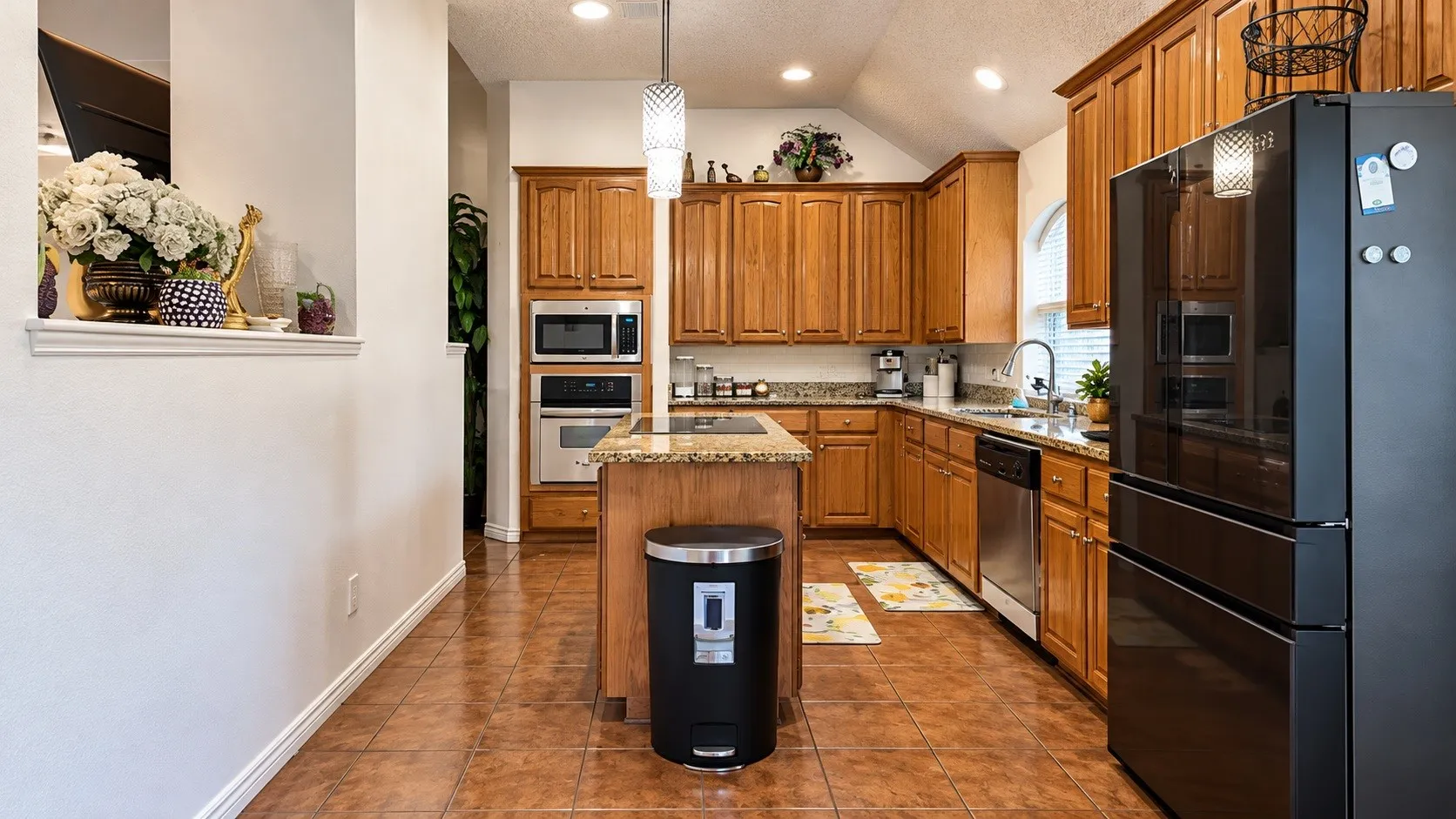 Kitchen featuring wood cabinetry, an integrated wall oven, a built-in microwave, stainless steel appliances, and a central island with a stone countertop