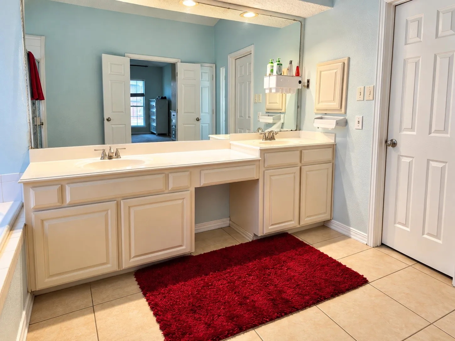 Dual vanity with integrated sinks, expansive counter space, wood-finish cabinetry, and tiled flooring