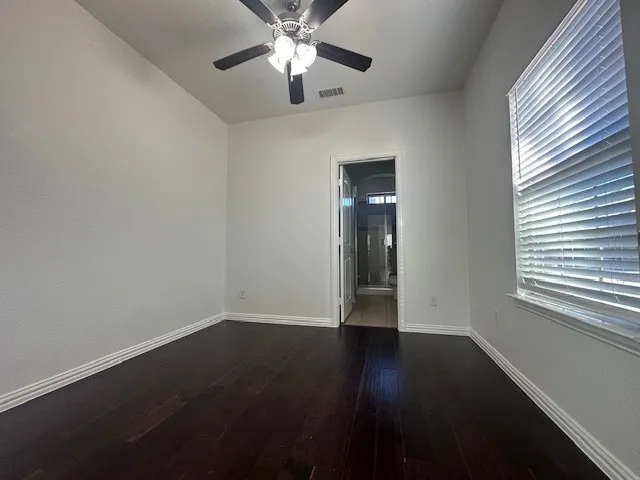 Wood-finish flooring, ceiling fan, window with blinds, and white trim throughout
