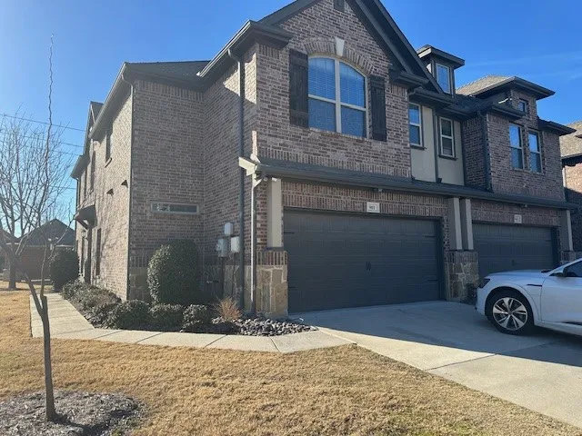 Brick and stone exterior with dark shutters, arched windows, and a two-car garage