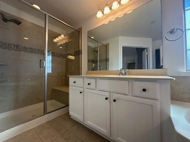 Glass-enclosed shower with a tiled bench and mosaic accent band