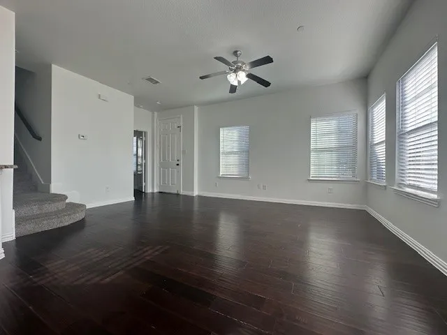 Spacious room with dark wood-finish flooring, multiple windows with blinds, a ceiling fan, and recessed lighting