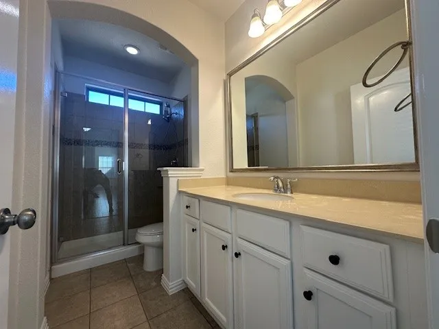 White vanity cabinetry with a single sink, light-toned countertop, and framed mirror