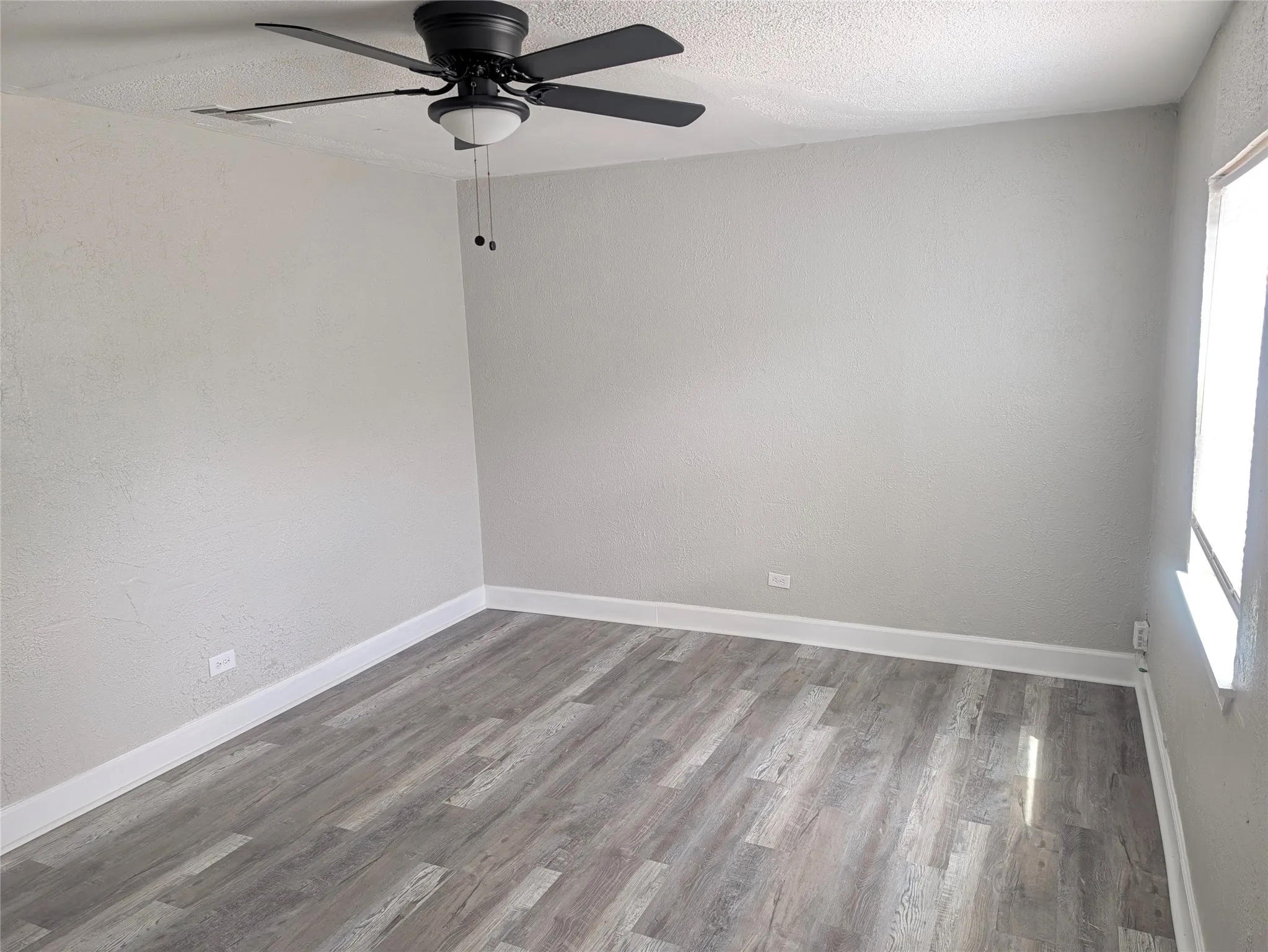 Neutral wall paint, wood-finish flooring, and ceiling fan with integrated lighting