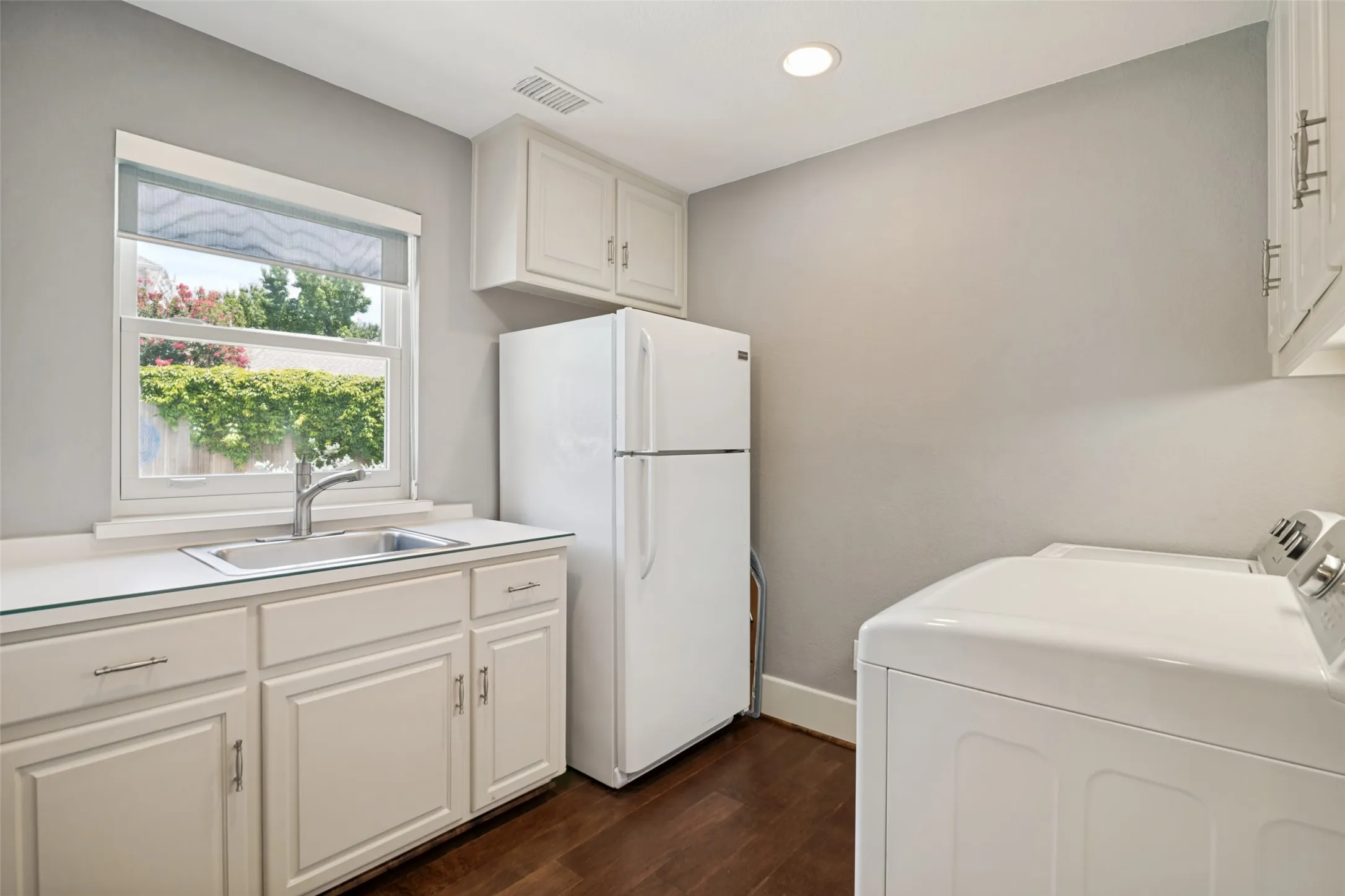 Light, bright laundry room with sink, room for fridge and cabinets.
