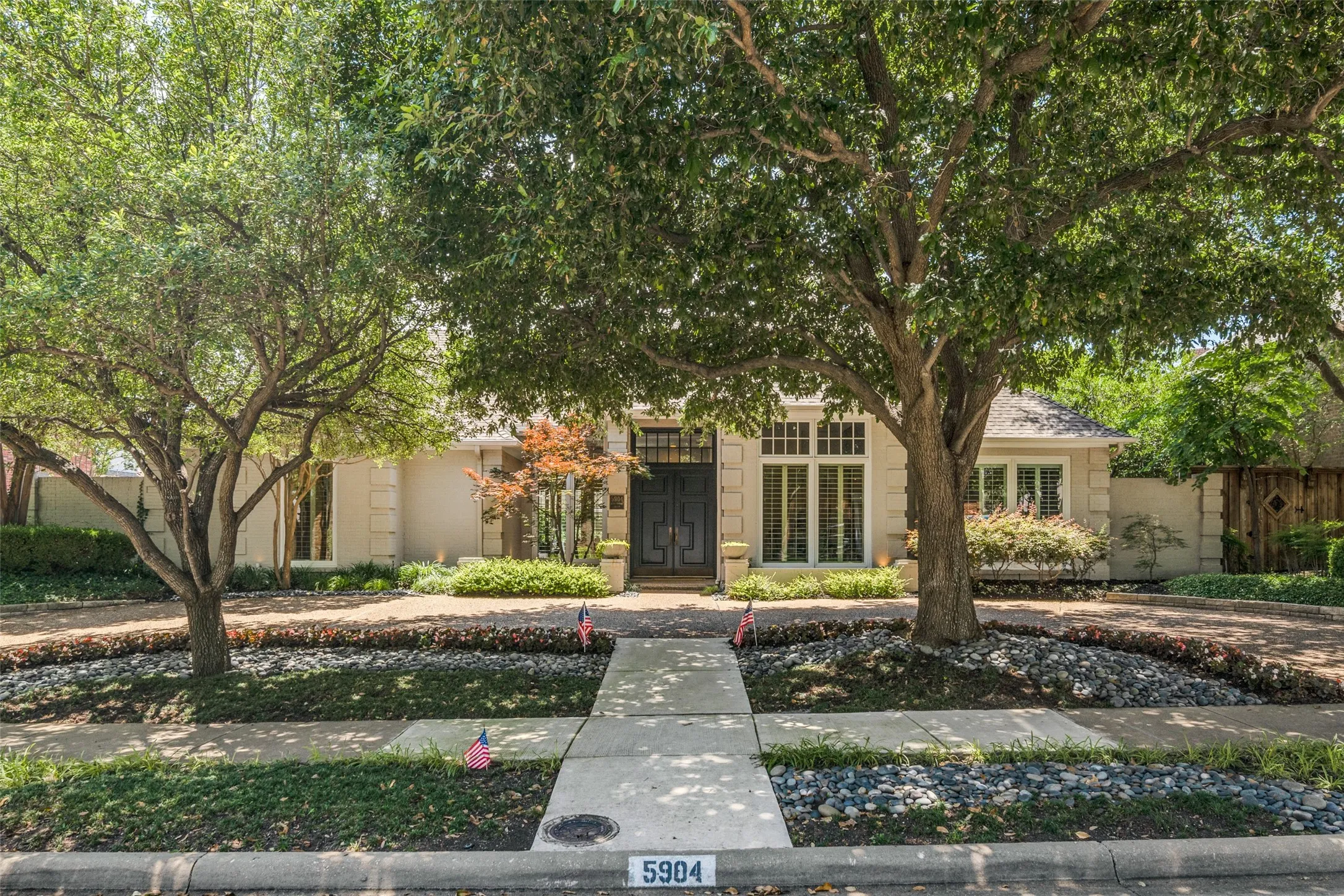 Tall trees frame the driveway for classic, inviting curb appeal.