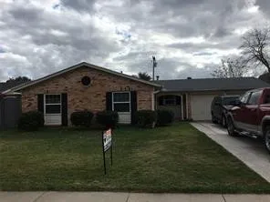 Brick facade with dark shutters, gabled roofline, and attached garage