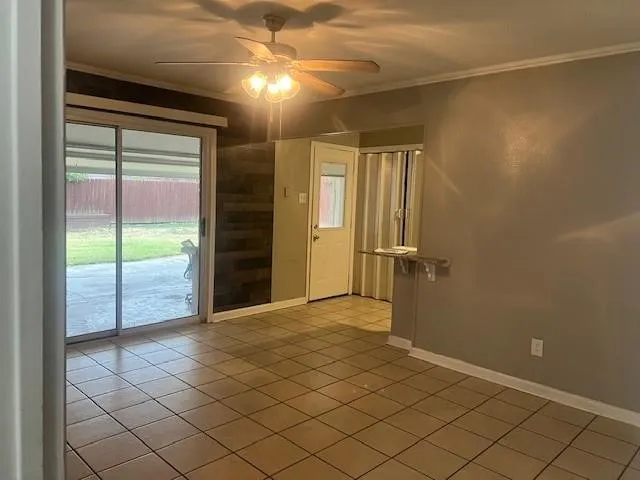 Tile flooring, ceiling fan with light fixture, sliding glass door, wood-finish accent wall, and built-in shelving