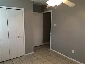 Neutral-toned wall finish, tile flooring, ceiling fan with integrated light, and bi-fold closet doors