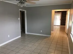 Spacious open-concept living area featuring neutral gray walls, ceramic tile flooring, and abundant natural light from multiple glass doors and windows