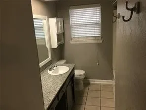 Bathroom featuring a vanity with an integrated sink, a window with blinds, and tile flooring