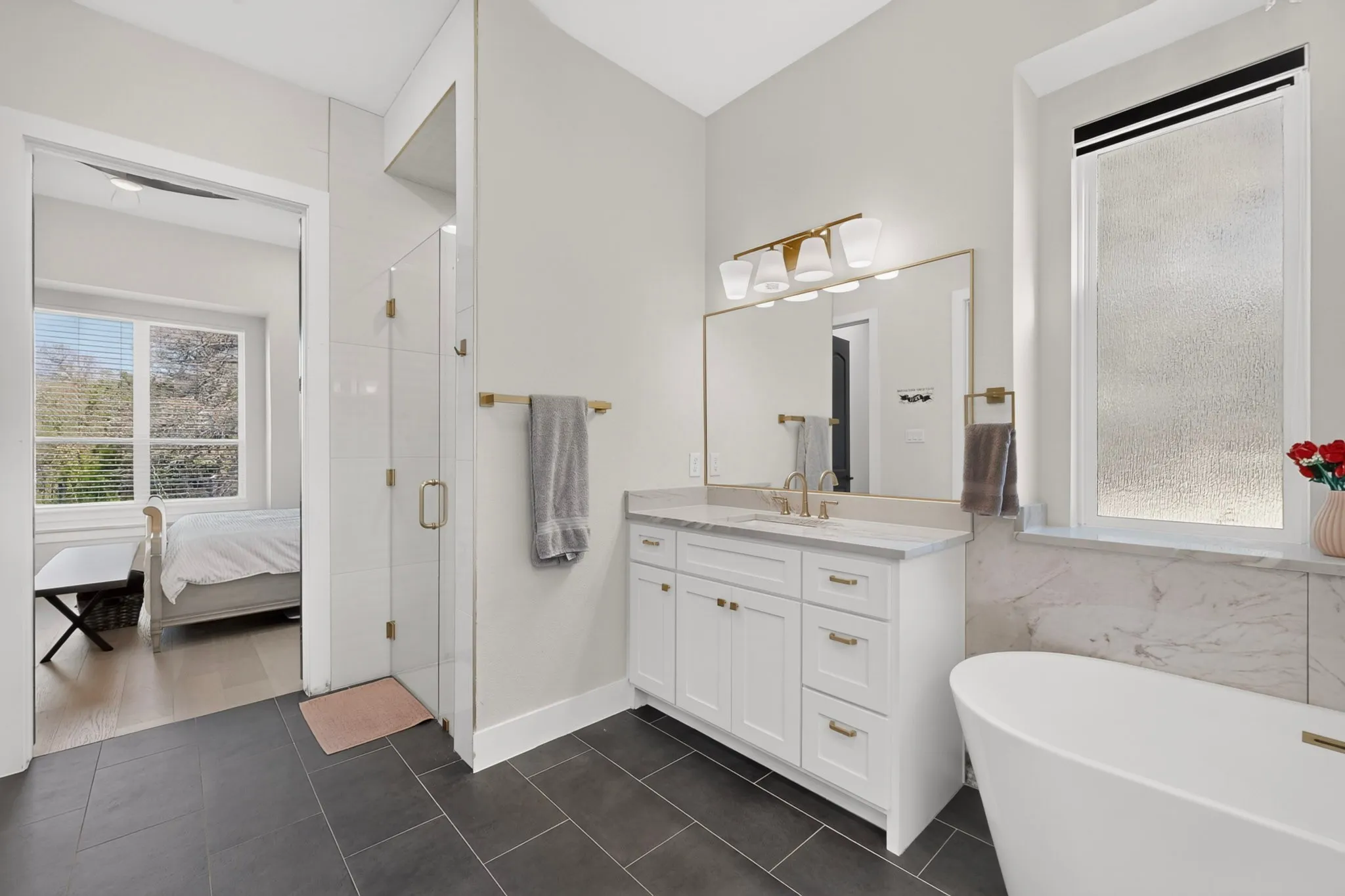 White vanity with gold-tone hardware, undermount sink, and marble countertop